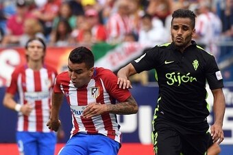 Atletico Madrid's Argentinian forward Angel Correa (L) kicks the ball past Sporting Gijon's Brazilian defender Douglas during the Spanish league football match Club Atletico de Madrid vs Real Sporting de Gijon at the Vicente Calderon stadium in Madrid on 