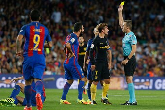 Referee shows a yellow card to Atletico Madrid's French forward Antoine Griezmann (2nd R) during the Spanish league football match FC Barcelona vs Atletico de Madrid at the Camp Nou stadium in Barcelona on September 21, 2016. / AFP / PAU BARRENA        (P