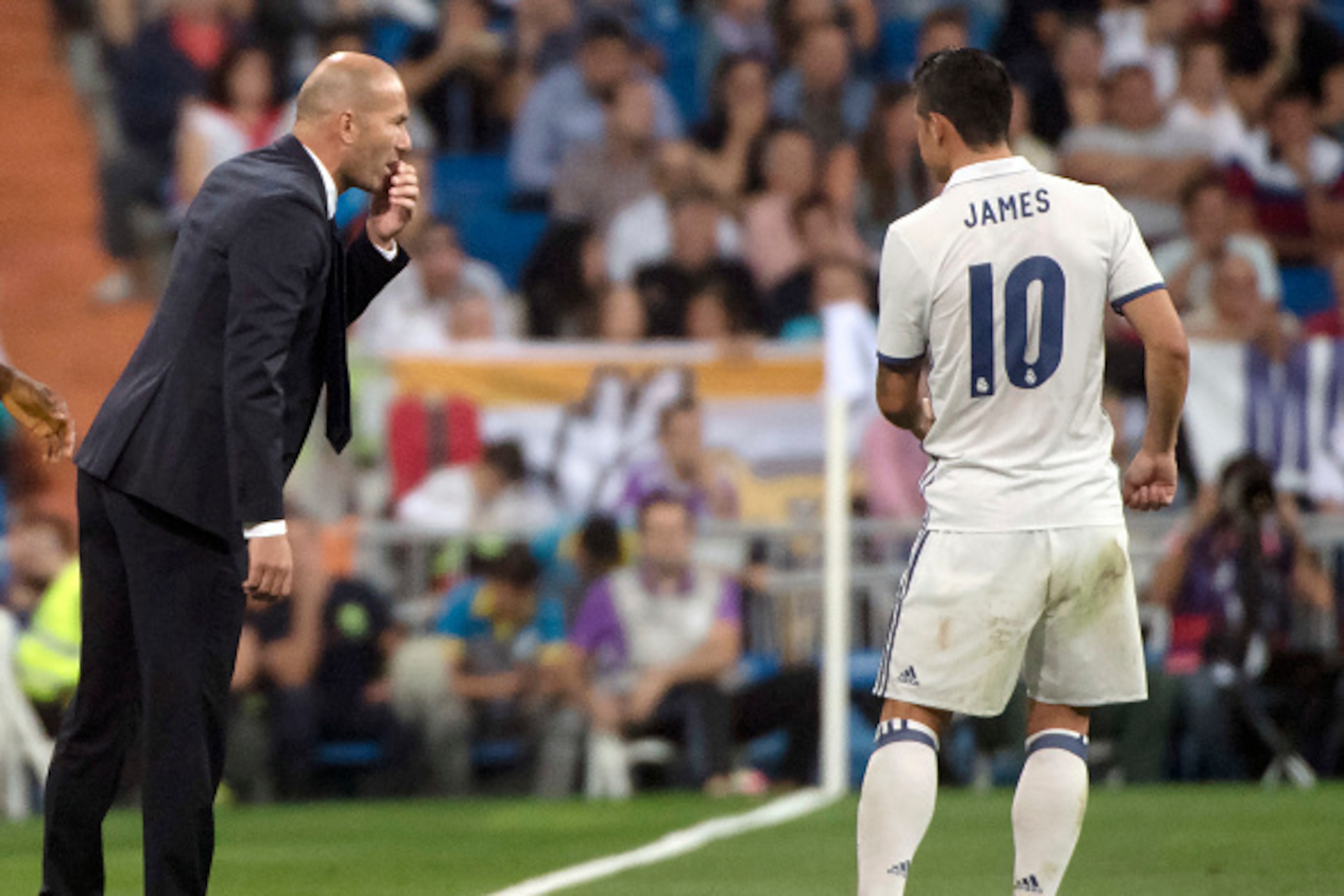 Real Madrid's French coach Zinedine Zidane (L) talks with Real Madrid's Colombian midfielder James Rodriguez during the Spanish league football match Real Madrid CF vs Villarreal CF at the Santiago Bernabeu stadium in Madrid on September 21, 2016. / AFP /