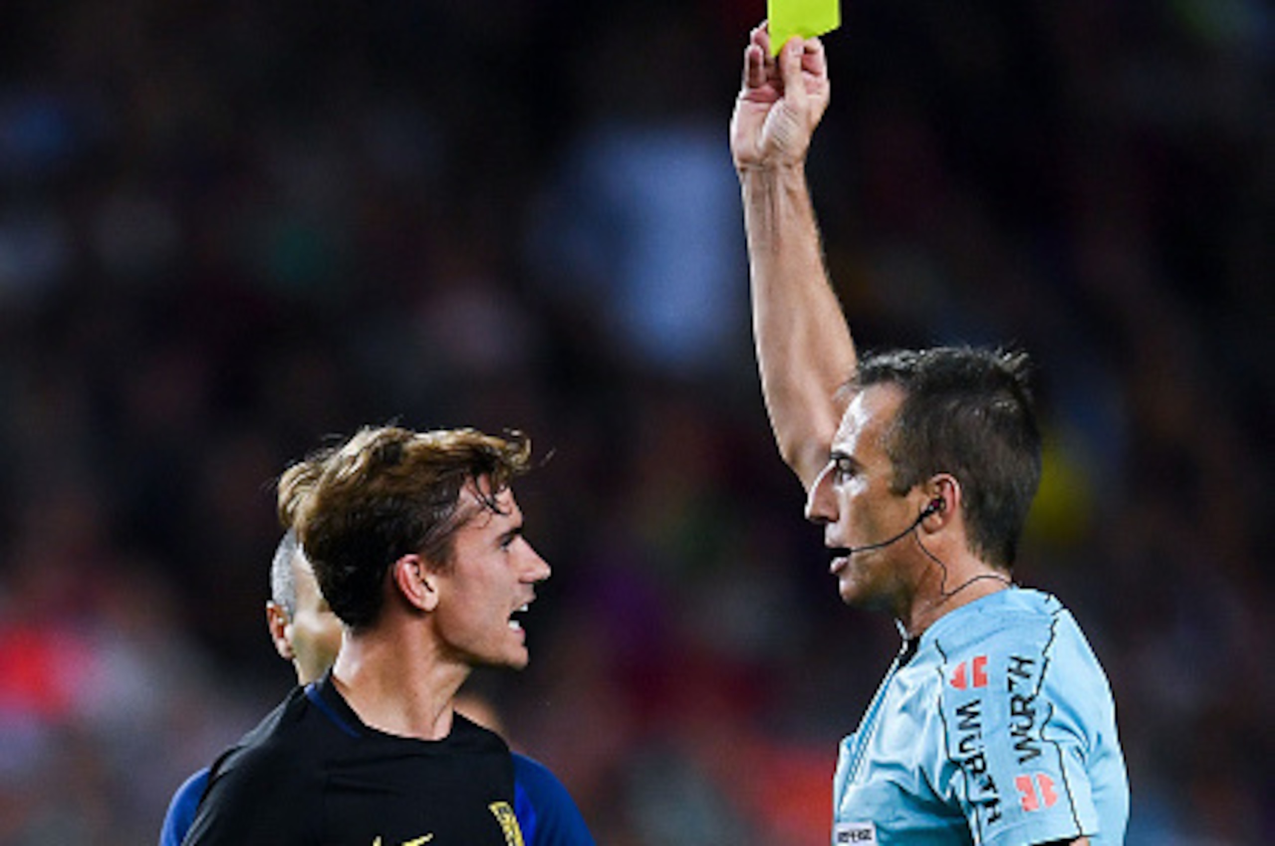 BARCELONA, SPAIN - SEPTEMBER 21:  Antoine Griezmann of Club Atletico de Madrid is shown a yellow card by the referee David Fernandez Borbalan after a challlenge on Ardan Turan of FC Barcelona, not in picture, during the La Liga match between FC Barcelona 