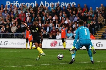 Manchester City's English midfielder Raheem Sterling (L) slots the ball past Swansea City's Polish goalkeeper Lukasz Fabianski (R) to score their third goal during the English Premier League football match between Swansea City and Manchester City at The L