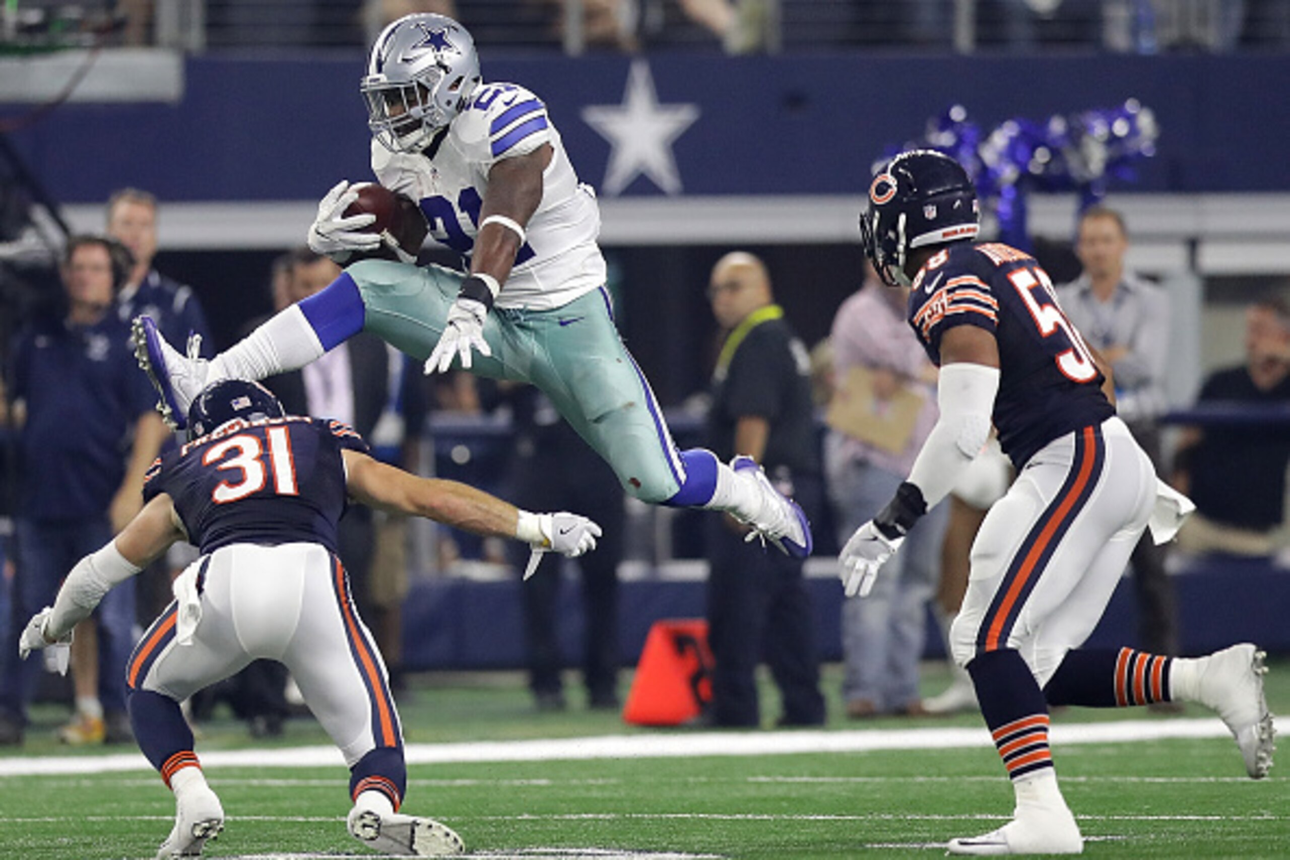 ARLINGTON, TX - SEPTEMBER 25:  Ezekiel Elliott #21 of the Dallas Cowboys jumps over the tackle attempt by Chris Prosinski #31 of the Chicago Bears in the fourth quarter at AT&T Stadium on September 25, 2016 in Arlington, Texas.  (Photo by Ronald Martinez/