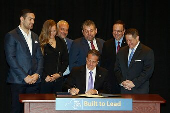 NEW YORK, NY - APRIL 14: New York Governor Andrew Cuomo is joined by (from left) UFC fighters Chris Weidman and Ronda Rousey, UFC CEO Lorenzo Fertitta, Madison Square Garden President James Dolan, Senator Joe Griffo and Assemblyman Joseph Morelle as he si