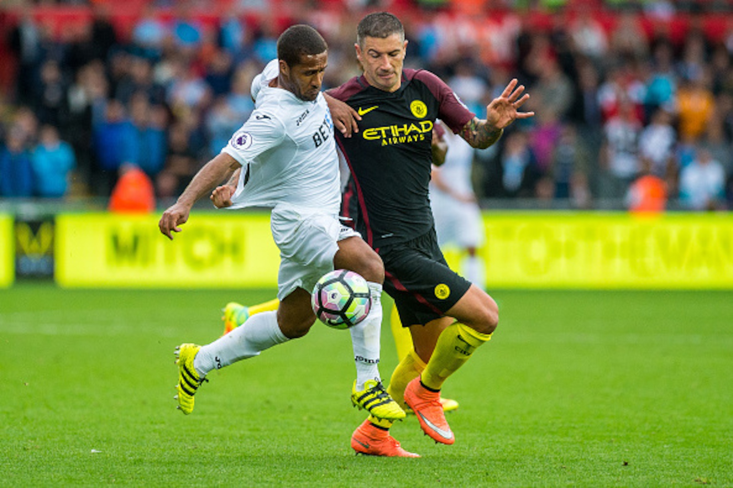 SWANSEA, WALES - SEPTEMBER 24: Wayne Routledge and Aleksandar Kolarov of Manchester City  battle for the ball during the Premier League match between Swansea City and Manchester City at The Liberty Stadium on September 24, 2016 in Swansea, Wales. (Photo b