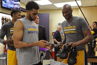 LOS ANGELES, CA - APRIL 13:  Kobe Bryant #24 of the Los Angeles Lakers signs a shoes for D'Angelo Russell #1 before the game against the Utah Jazz at STAPLES Center on April 13, 2016 in Los Angeles, California. NOTE TO USER: User expressly acknowledges an