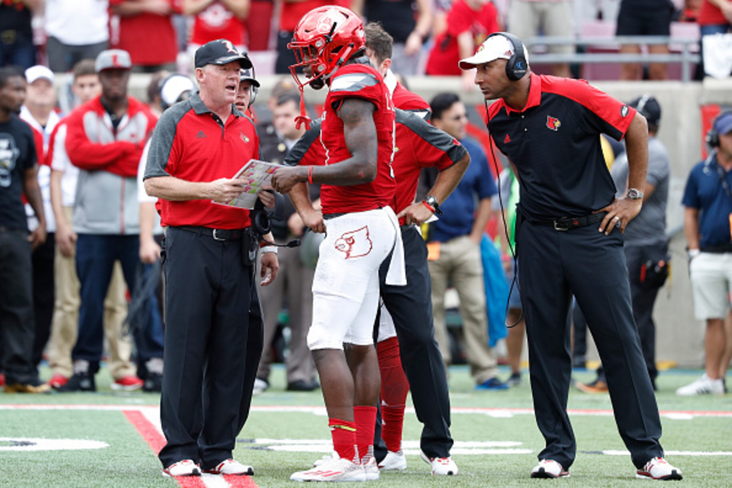 LOUISVILLE, KY - SEPTEMBER 17: Louisville Cardinals head coach Bobby Petrino and co-offensive coordinator Lonnie Galloway talk with quarterback Lamar Jackson #8 during the game against the Florida State Seminoles at Papa John's Cardinal Stadium on Septemb