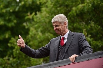 Arsenal's French manager Arsene Wenger gives the thums up to the fans as he stands on the top deck of an open-topped bus during the Arsenal victory parade in London on May 31, 2015, following their win in the English FA Cup final football match on May 30,