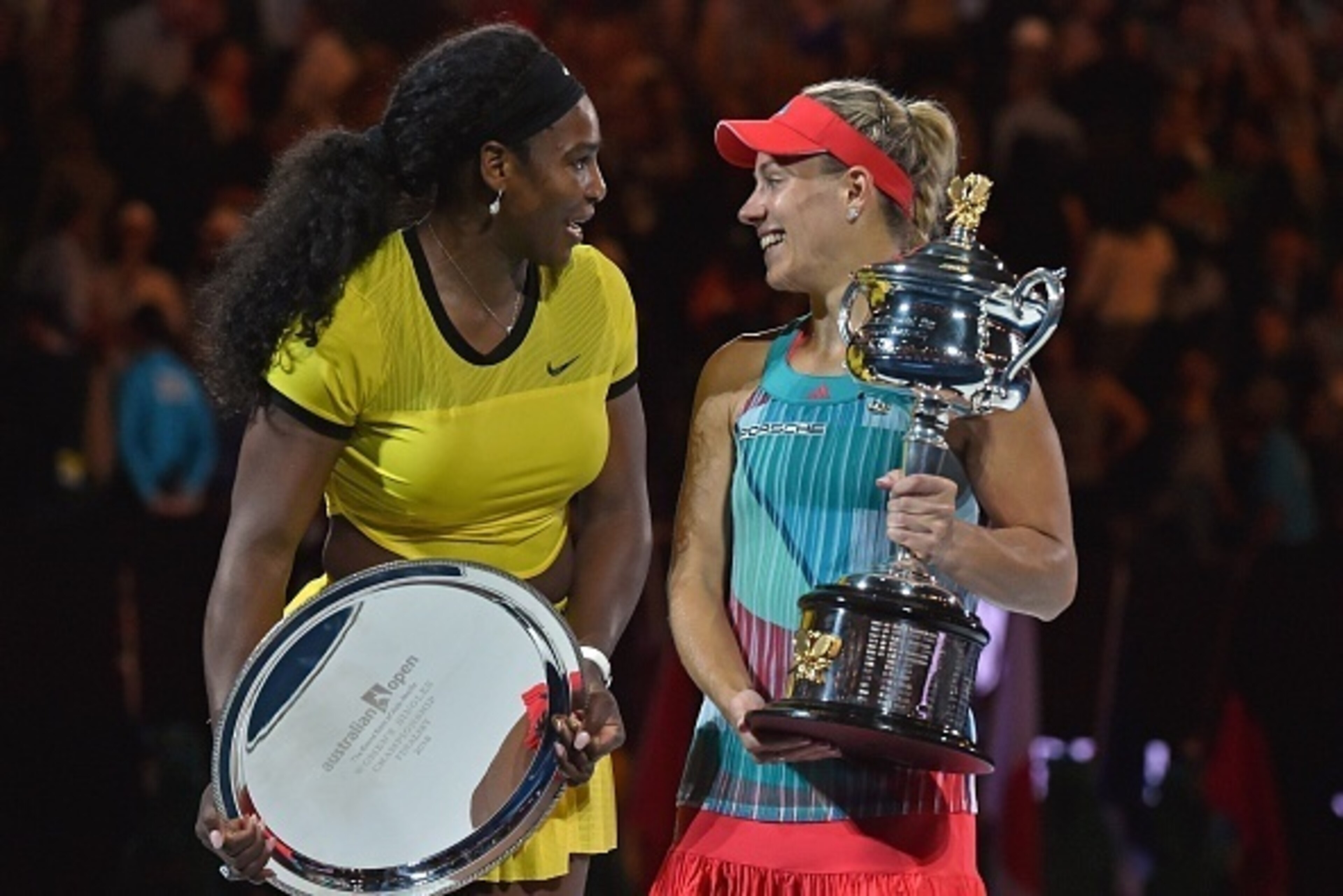 Angelique Kerber of Germany (R) holds the winner's trophy during the awards ceremony following her victory over Serena Williams of the US (L) in their women's singles final match on day 13 of the 2016 Australian Open tennis tournament in Melbourne on Janu