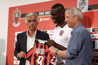 Nice's football club new signing Italian forward Mario Balotelli (C) smiles as he poses with his new jersey between Nice's French club president Jean-Pierre Rivere (L) and Nice's Swiss head coach Lucien Favre at the end of a press conference, on September