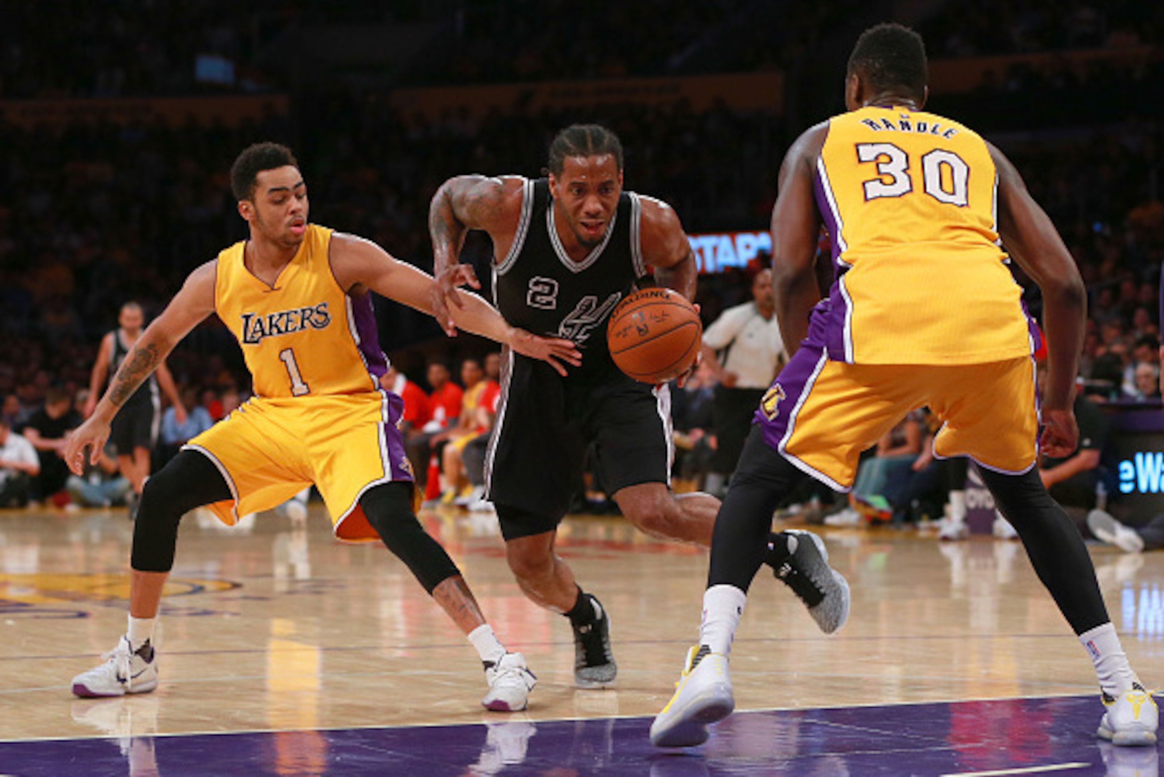 LOS ANGELES, CA - JANUARY 22: Kawhi Leonard #2 of the San Antonio Spurs dribbles to the basket against D'Angelo Russell #1 and Julius Randle #30 of the Los Angeles Lakers in the second half during the NBA game at Staples Center on January 22, 2016 in Los 