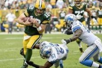 Sep 25, 2016; Green Bay, WI, USA;  Green Bay Packers quarterback Aaron Rodgers (12) runs for a first down before being tackled by Detroit Lions defensive end Brandon Copeland (51) and linebacker Tahir Whitehead (59) in the third quarter at Lambeau Field. 