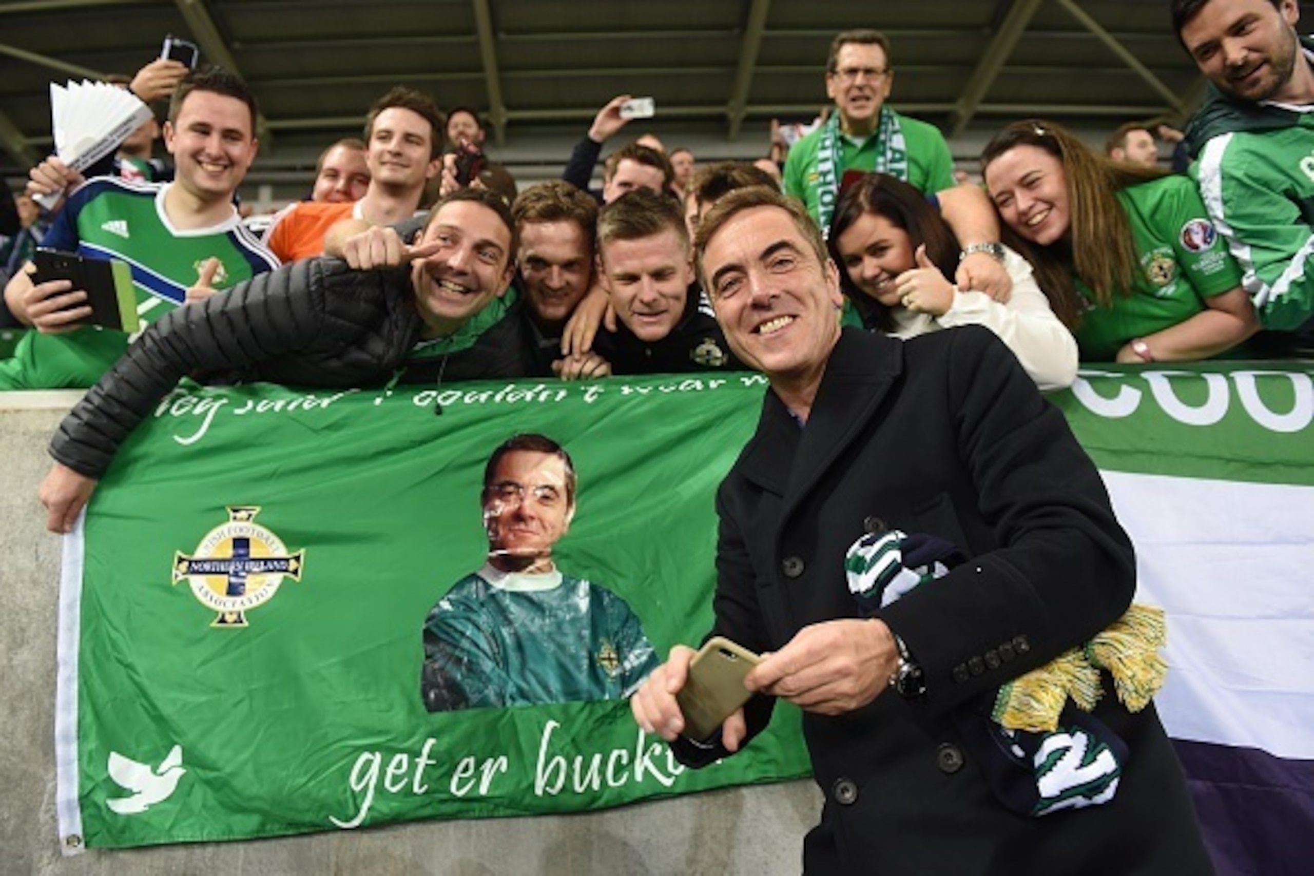 BELFAST, NORTHERN IRELAND - OCTOBER 08: Jimmy Nesbitt takes a photograph with fans and a poster featuring himself as he attends the FIFA 2018 World Cup Qualifier between Northern Ireland and San Marino at Windsor Park on October 8, 2016 in Belfast, Northe