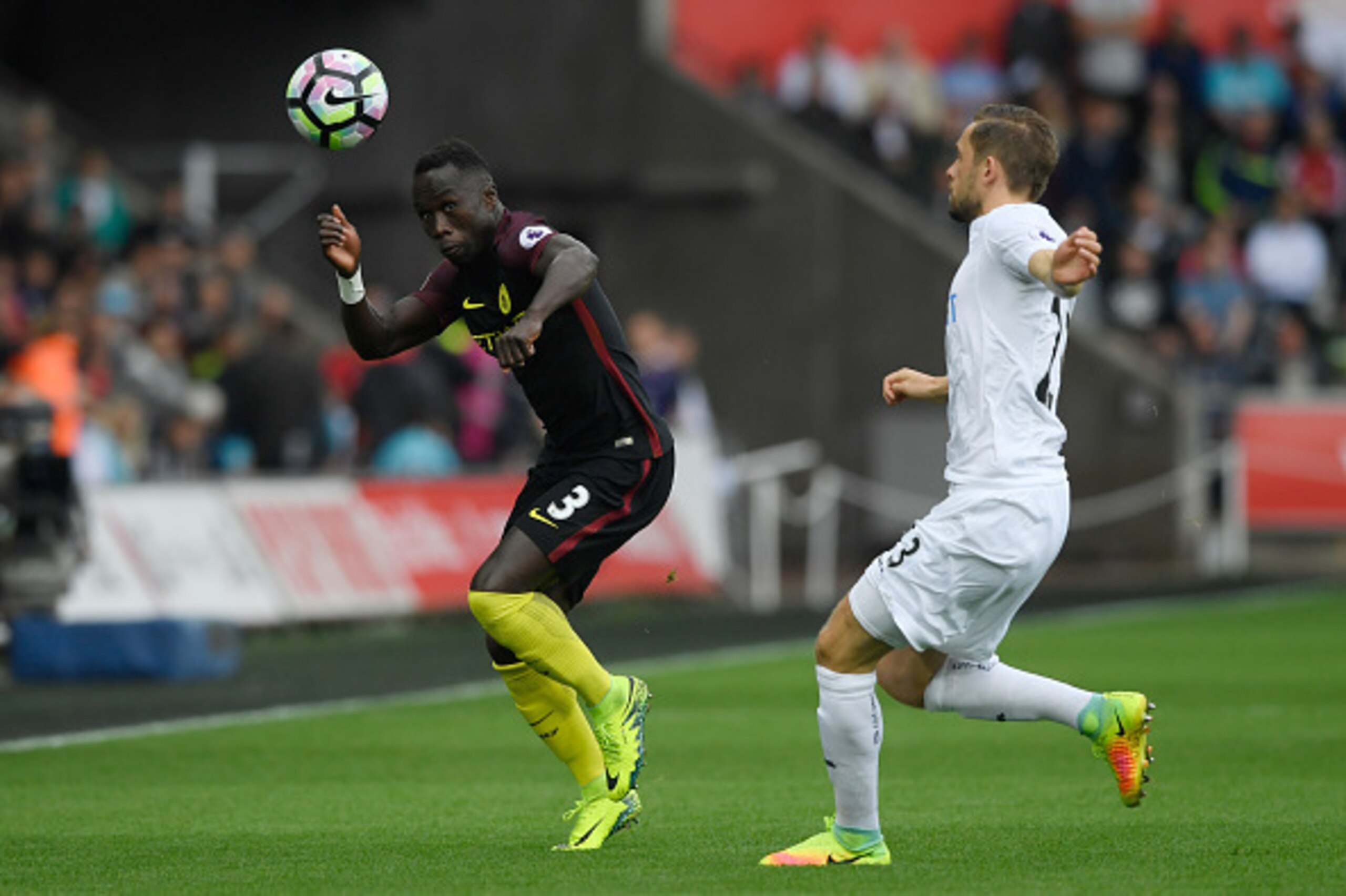 SWANSEA, WALES - SEPTEMBER 24:  Bacary Sagna of Manchester City beats Gylfi Sigurdsson of Swansea City to the ball during the Premier League match between Swansea City and Manchester City at the Liberty Stadium on September 24, 2016 in Swansea, Wales.  (P