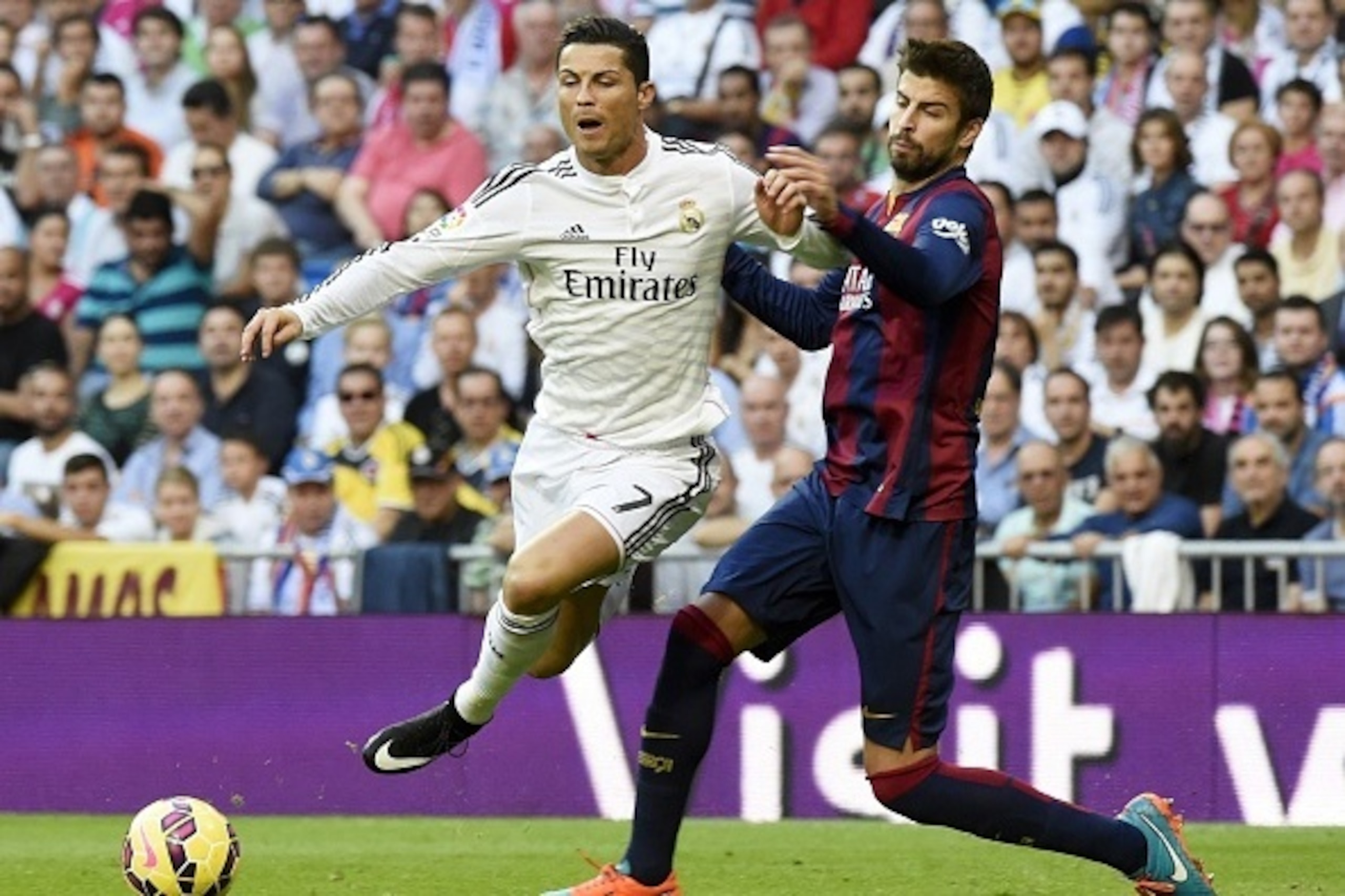 Real Madrid's Portuguese forward Cristiano Ronaldo (L) vies with Barcelona's defender Gerard Pique during the Spanish league 'Clasico' football match Real Madrid CF vs FC Barcelona at the Santiago Bernabeu stadium in Madrid on October 25, 2014.  AFP PHOTO