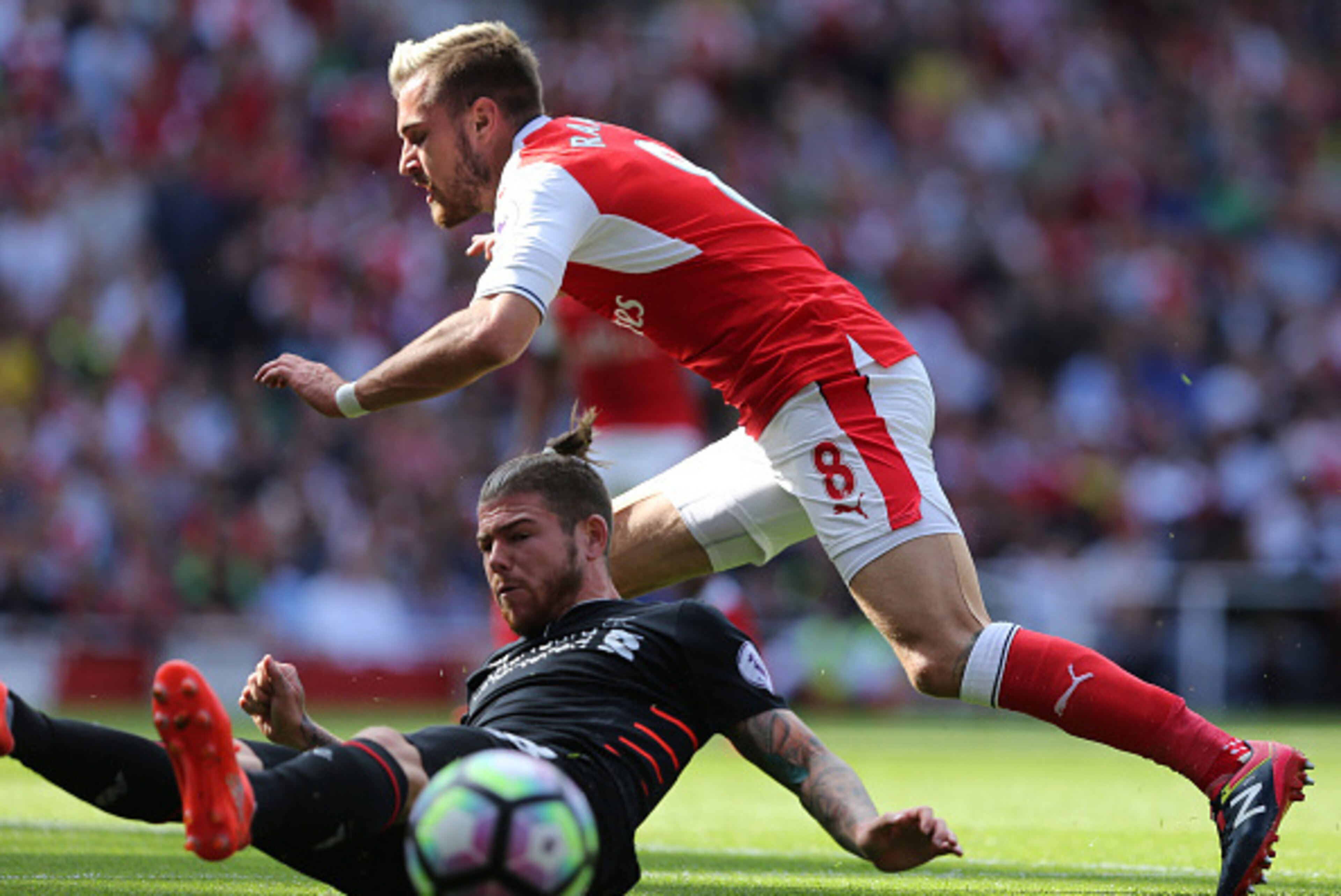 Liverpool's Spanish defender Alberto Moreno (L) slides in to tackle Arsenal's Welsh midfielder Aaron Ramsey (R) during the English Premier League football match between Arsenal and Liverpool at the Emirates Stadium in London on August 14, 2016.  / AFP / L