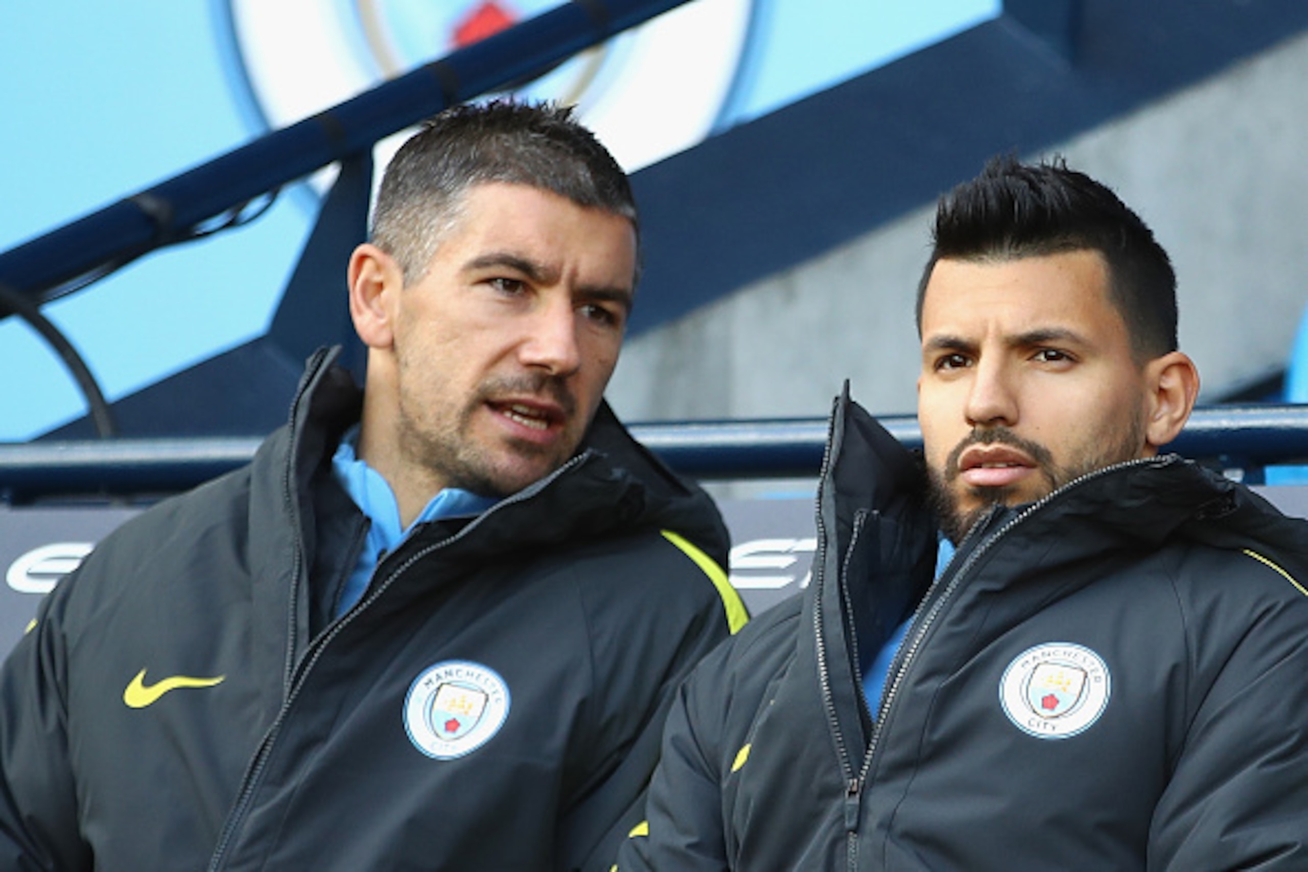 MANCHESTER, ENGLAND - OCTOBER 15:  Aleksander Kolorov of Manchester City (L) and Sergio Aguero of Manchester City (R) speak on the bench during the Premier League match between Manchester City and Everton at Etihad Stadium on October 15, 2016 in Mancheste