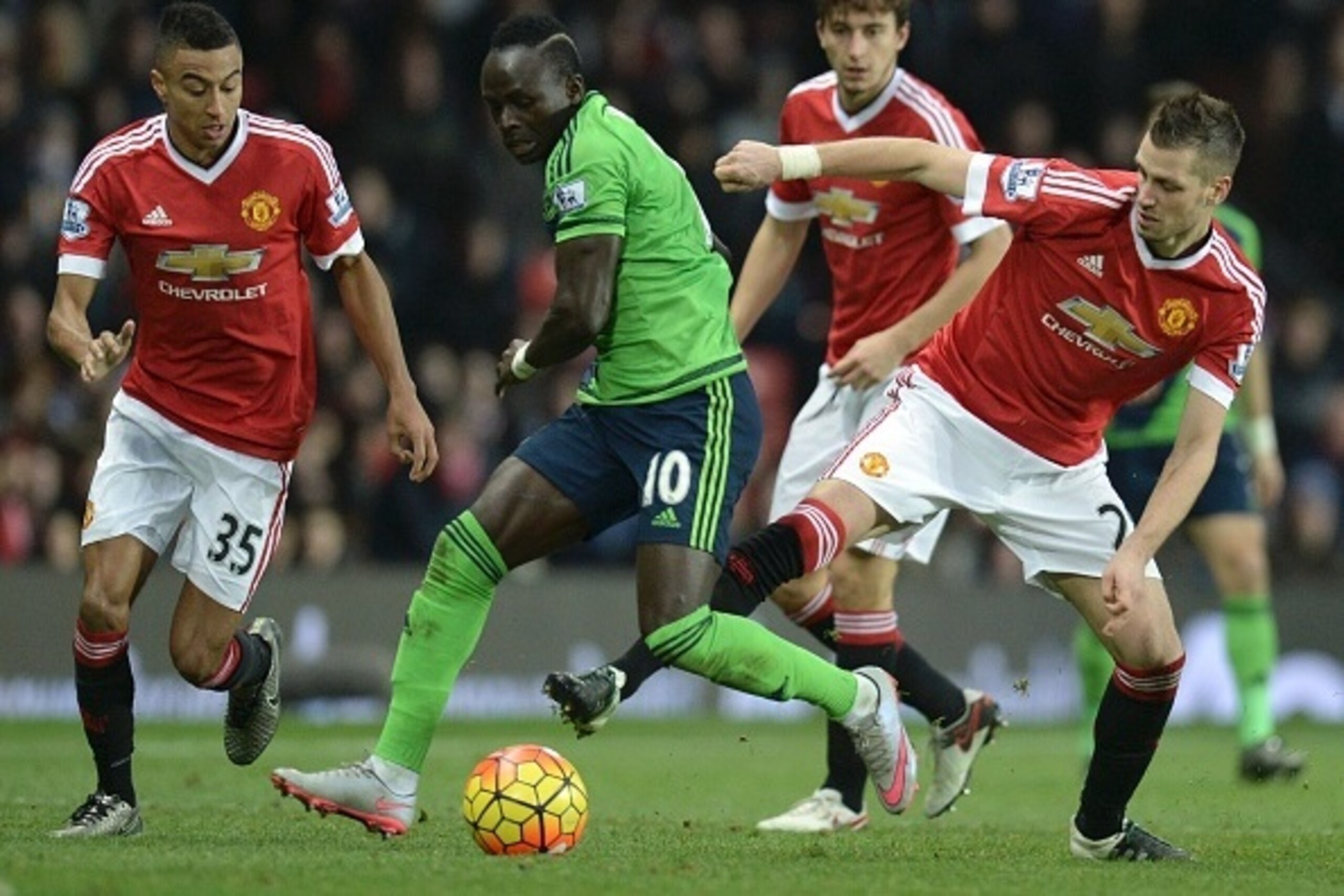 Southampton's Senegalese midfielder Sadio Mane (C) tries to evade tackles from Manchester United's French midfielder Morgan Schneiderlin (R) and Manchester United's English midfielder Jesse Lingard (L) during the English Premier League football match betw