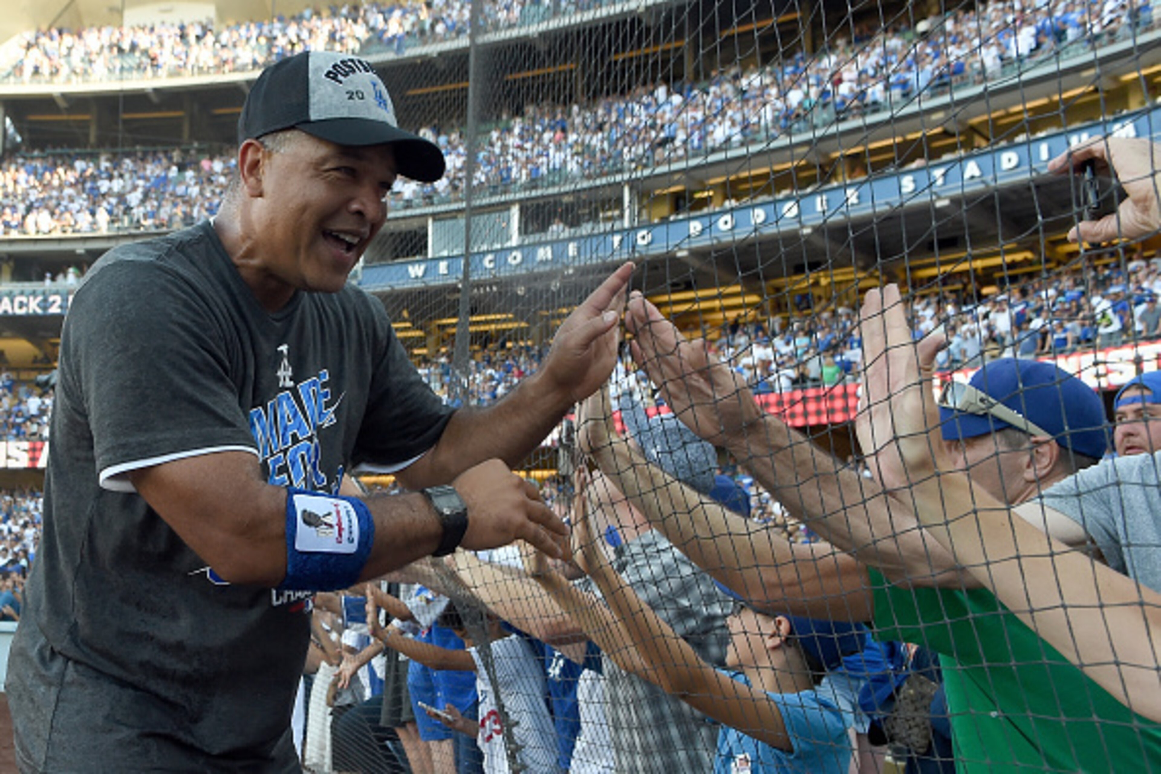 LOS ANGELES, CA - SEPTEMBER 25: Manager Dave Roberts of the Los Angeles Dodgers celebrates with fans after a 4-3 win over the Colorado Rockies at Dodger Stadium on September 25, 2016 in Los Angeles, California. The Los Angeles Dodgers clinch the division LOS ANGELES, CA - SEPTEMBER 25: Manager Dave Roberts of the Los Angeles Dodgers celebrates with fans after a 4-3 win over the Colorado Rockies at Dodger Stadium on September 25, 2016 in Los Angeles, California. The Los Angeles Dodgers clinch the division