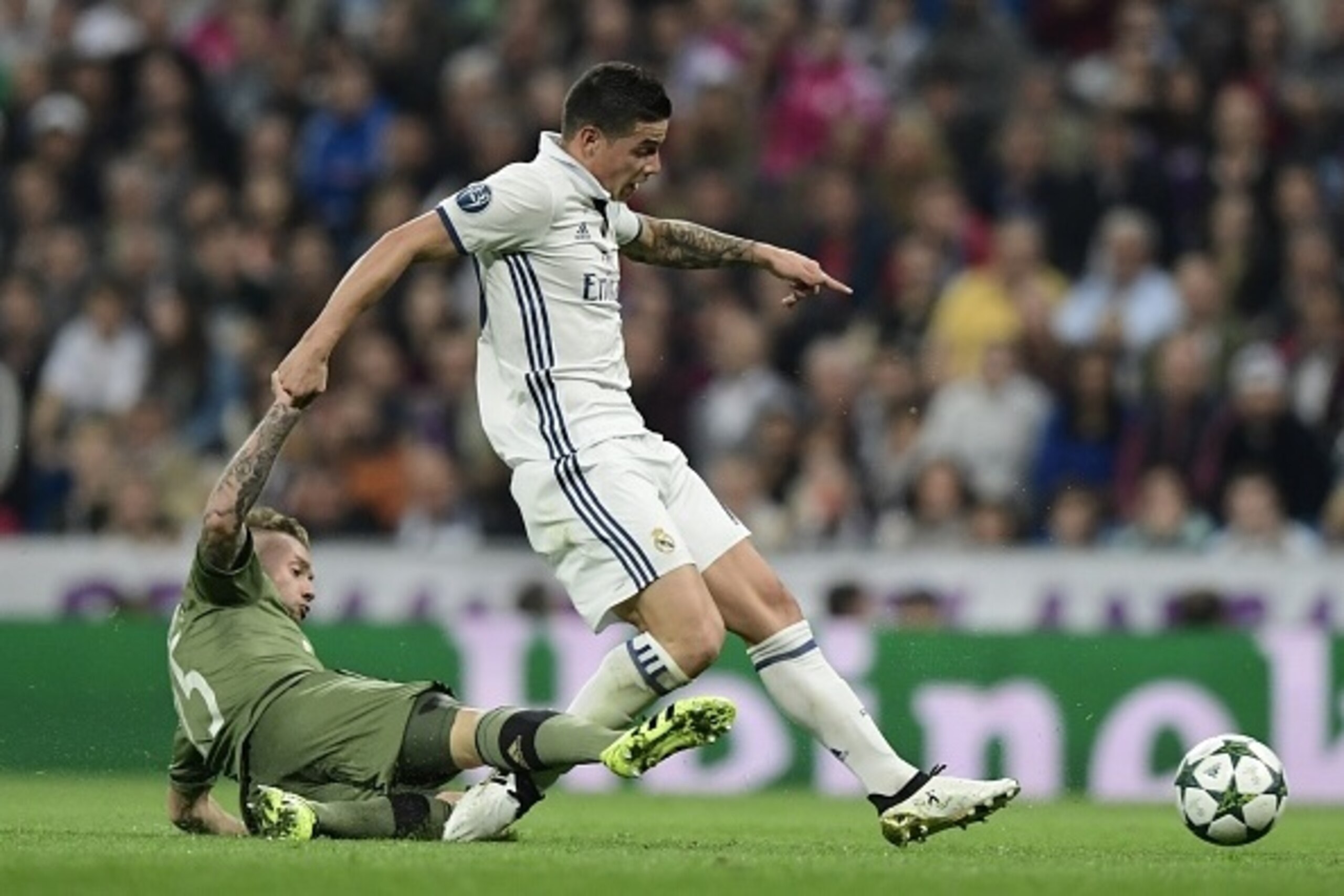 Real Madrid's Colombian midfielder James Rodriguez (L) is tackled by Legia Warszawa's French midfielder Thibault Moulin during the UEFA Champions League football match Real Madrid CF vs Legia  Legia Warszawa at the Santiago Bernabeu stadium in Madrid on O