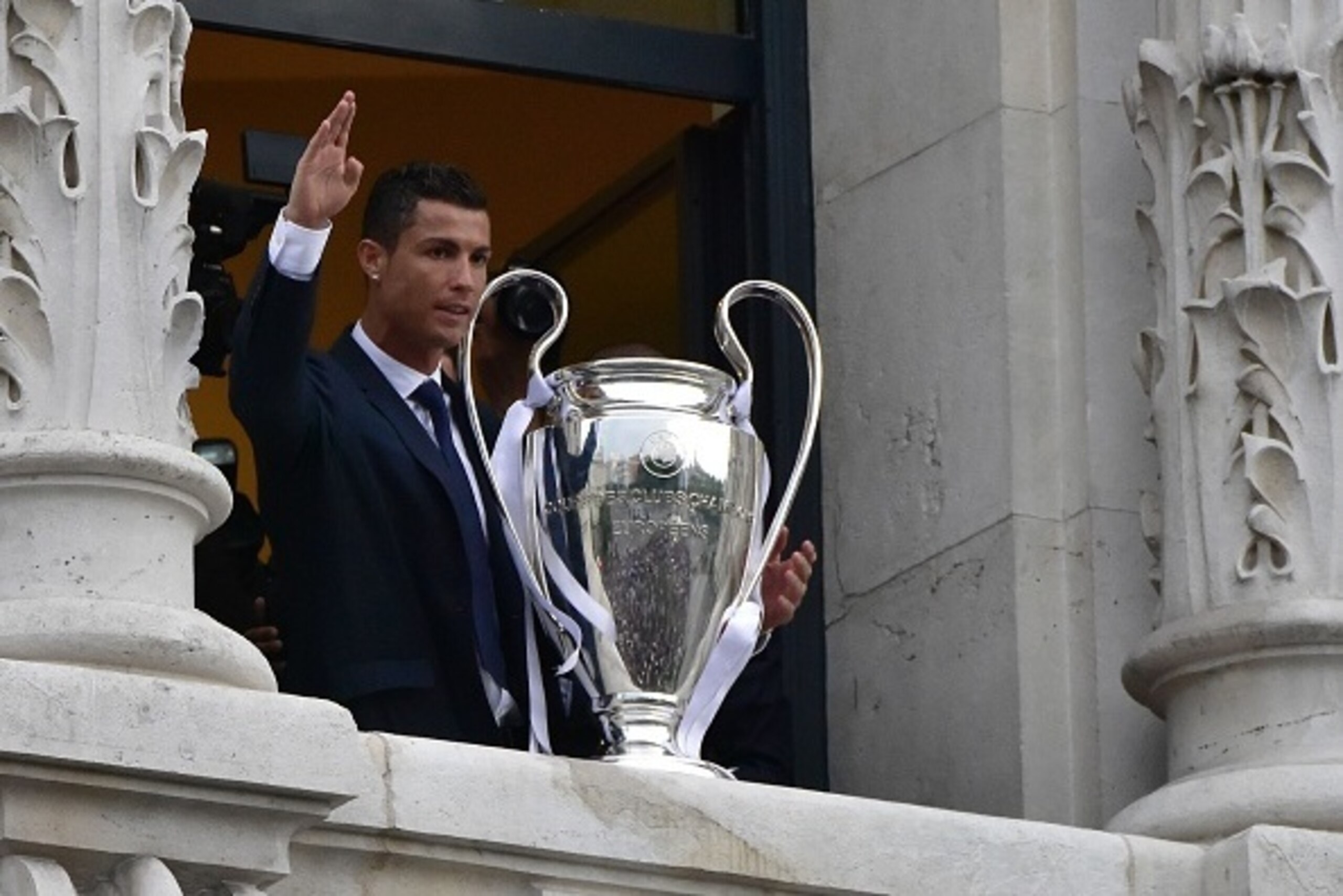 Real Madrid's Portuguese forward Cristiano Ronaldo waves as he shows the trophy from Madrid town hall's balcony on May 29, 2016 the day after winning the UEFA Champions League final foobtall match against Club Atletico de Madrid, held in Milan, Italy on M