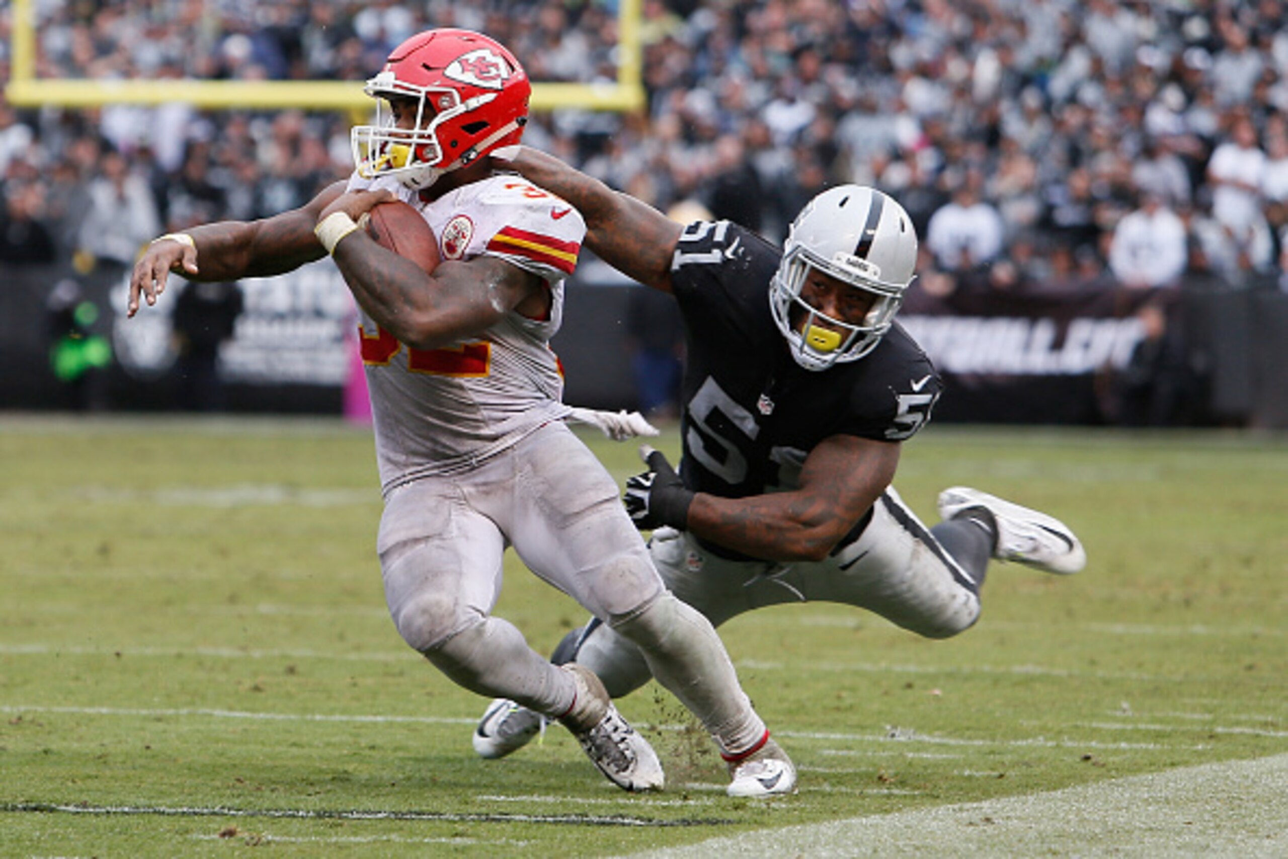 OAKLAND, CA - OCTOBER 16:  Spencer Ware #32 of the Kansas City Chiefs breaks a tackle by Bruce Irvin #51 of the Oakland Raiders during their NFL game at Oakland-Alameda County Coliseum on October 16, 2016 in Oakland, California.  (Photo by Brian Bahr/Gett