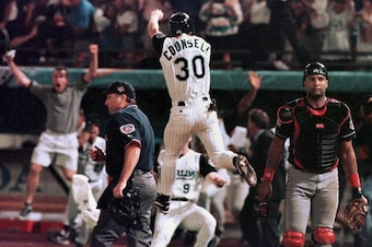 MIAMI, :  Florida Marlins player Craig Counsell jumps in the air after crossing the plate with the winning run as Cleveland Indians catcher Sandy Alomar (R) walks off the field at the end of game seven of the World Series 26 October at Pro Player Stadium.