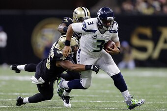 NEW ORLEANS, LA - OCTOBER 30: Russell Wilson #3 of the Seattle Seahawks runs with the ball as Craig Robertson #52 of the New Orleans Saints and Vonn Bell #48 defend during the second half of a game at the Mercedes-Benz Superdome on October 30, 2016 in New