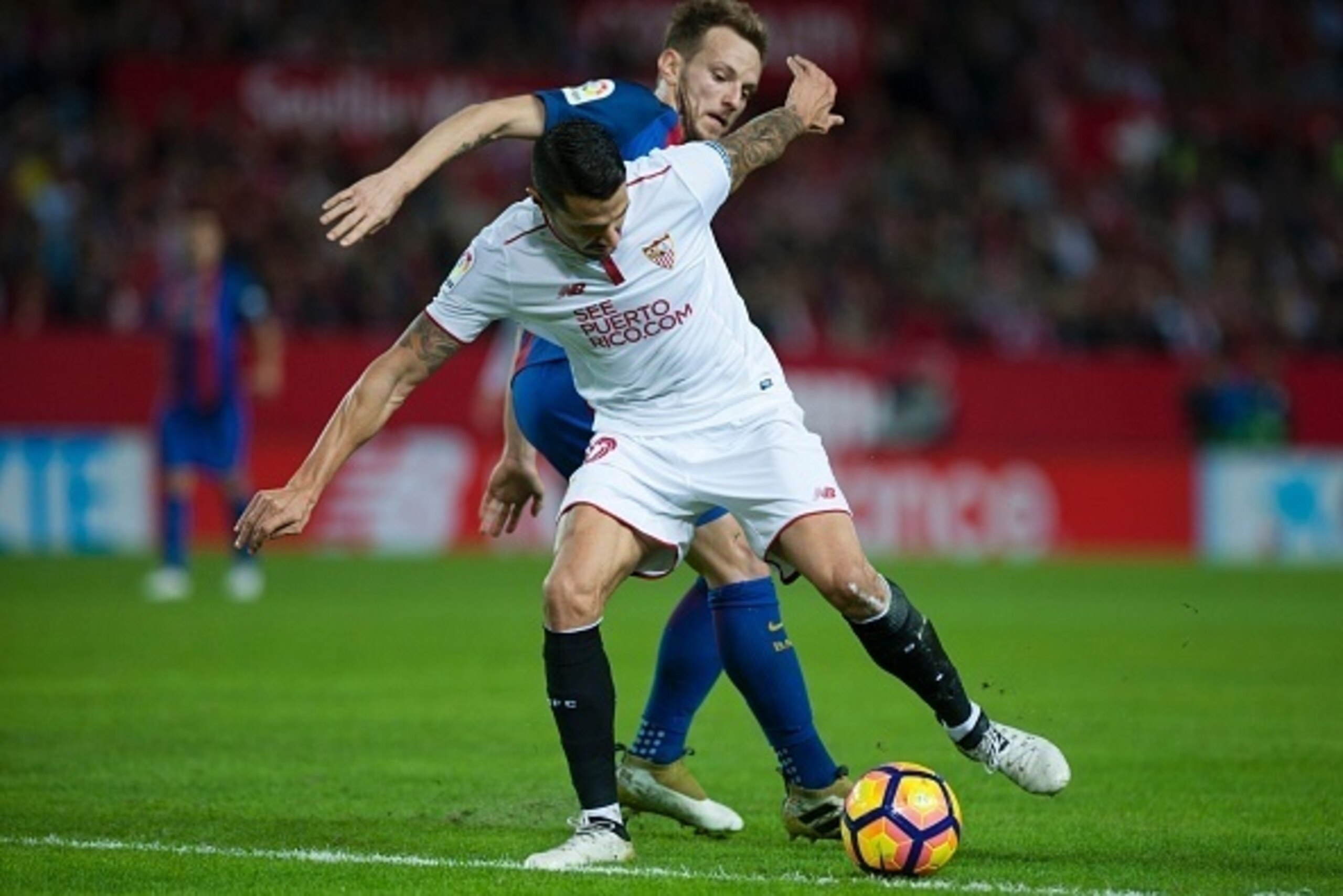 Sevilla's midfielder Vitolo (L) vies with Barcelona's Croatian midfielder Ivan Rakitic  during the Spanish league football match Sevilla FC vs FC Barcelona at the Ramon Sanchez Pizjuan stadium in Sevilla on November 6, 2016. / AFP / JORGE GUERRERO        