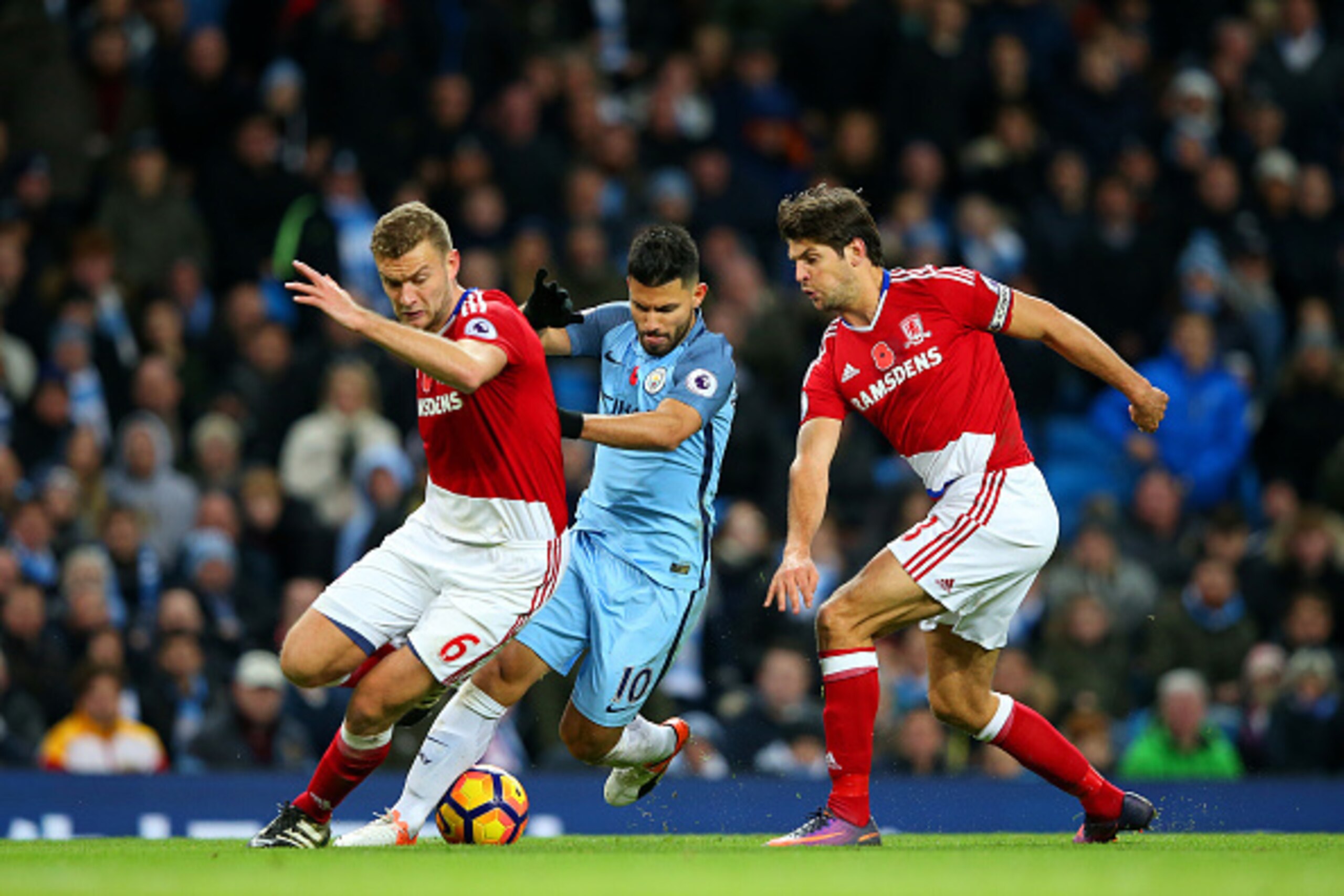 MANCHESTER, ENGLAND - NOVEMBER 05:  Sergio Aguero of Manchester City (C) attempts to take the ball past Ben Gibson of Middlesbrough (L) and Marten de Roon of Middlesbrough (R) during the Premier League match between Manchester City and Middlesbrough at Et
