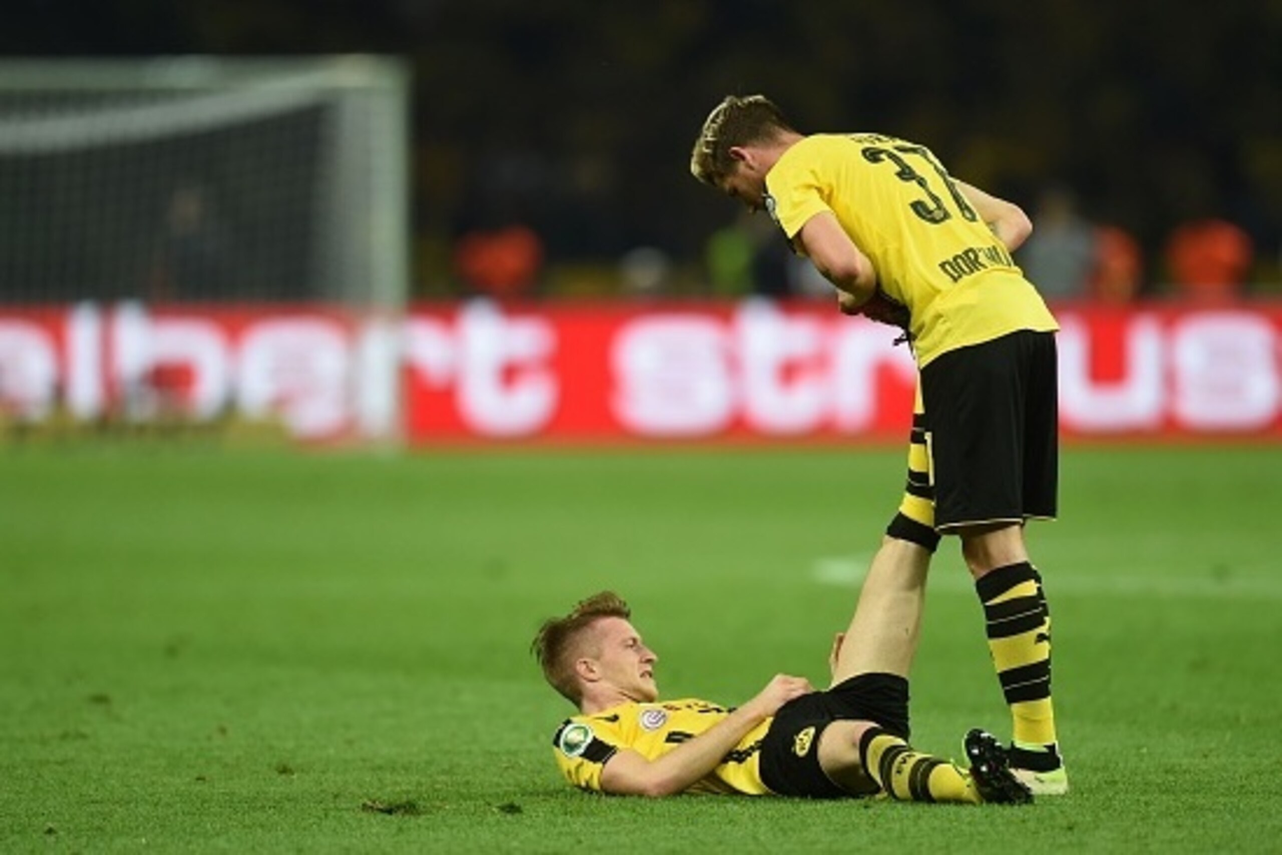 Dortmund's striker Marco Reus (L) is being helped by Dortmund's defender Erik Durm during the German Cup (DFB Pokal) final football match Bayern Munich vs Borussia Dortmund at the Olympic stadium in Berlin on May 21, 2016. / AFP / Christof STACHE / RESTRI
