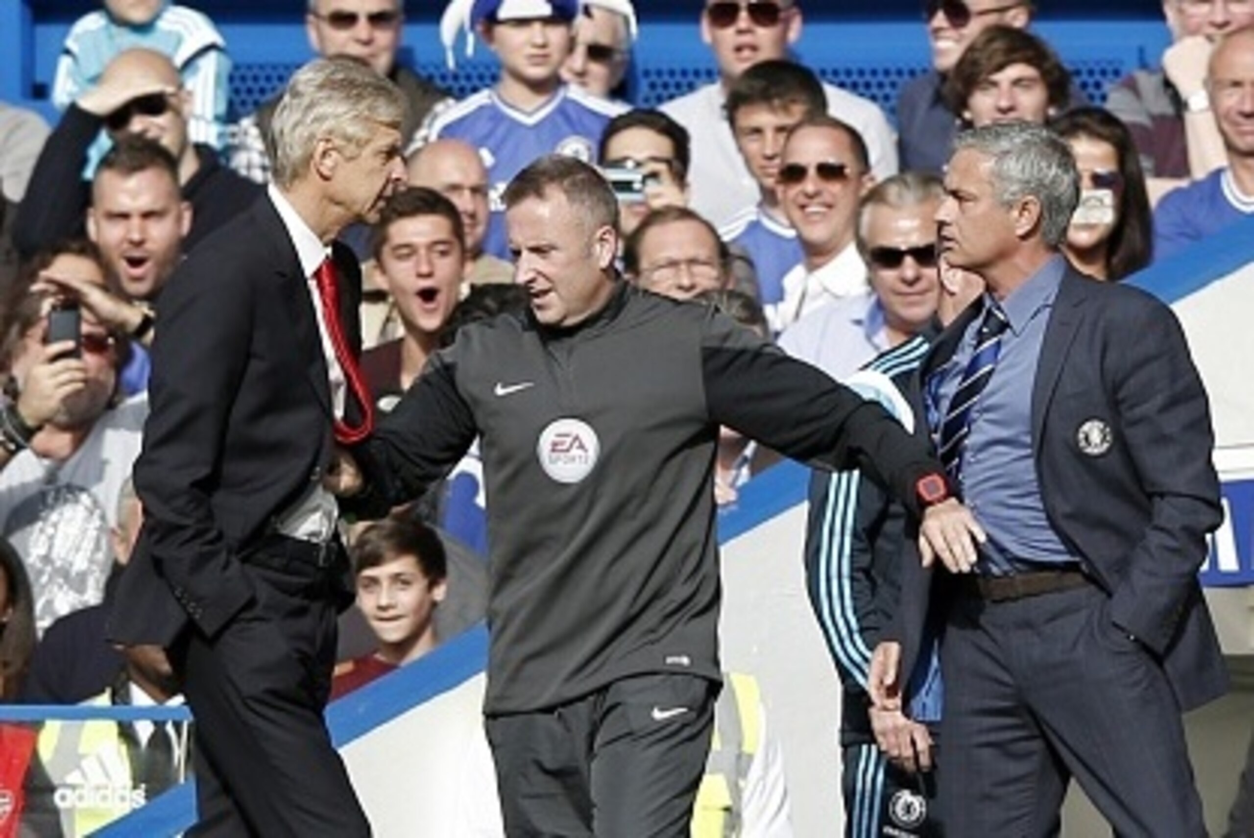 Chelsea's Portuguese manager Jose Mourinho (R) and Arsenal's French manager Arsene Wenger (L) are kept apart by the fourth official Jonathan Moss during the English Premier League football match between Chelsea and Arsenal at Stamford Bridge in London on 