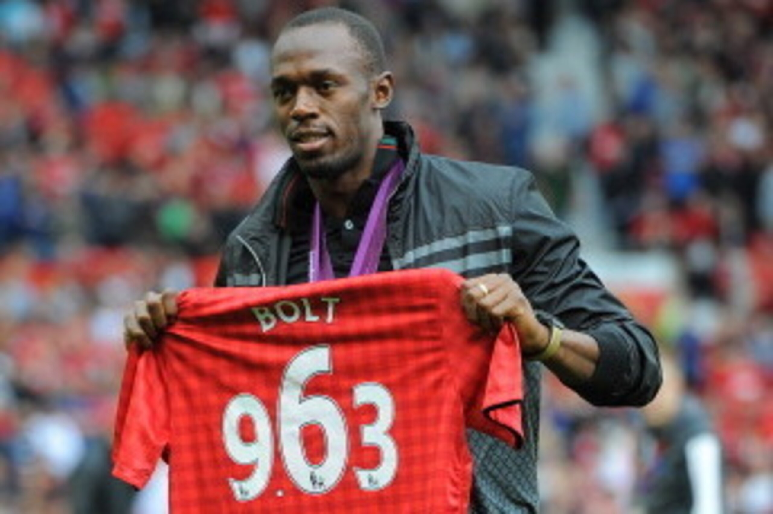 Manchester United supporter, Jamaican Olympic sprint champion Usain Bolt on the pitch with a replica shirt displaying the time in which he won the 100m Final before the English Premier League football match between Manchester United and Fulham at Old Traf