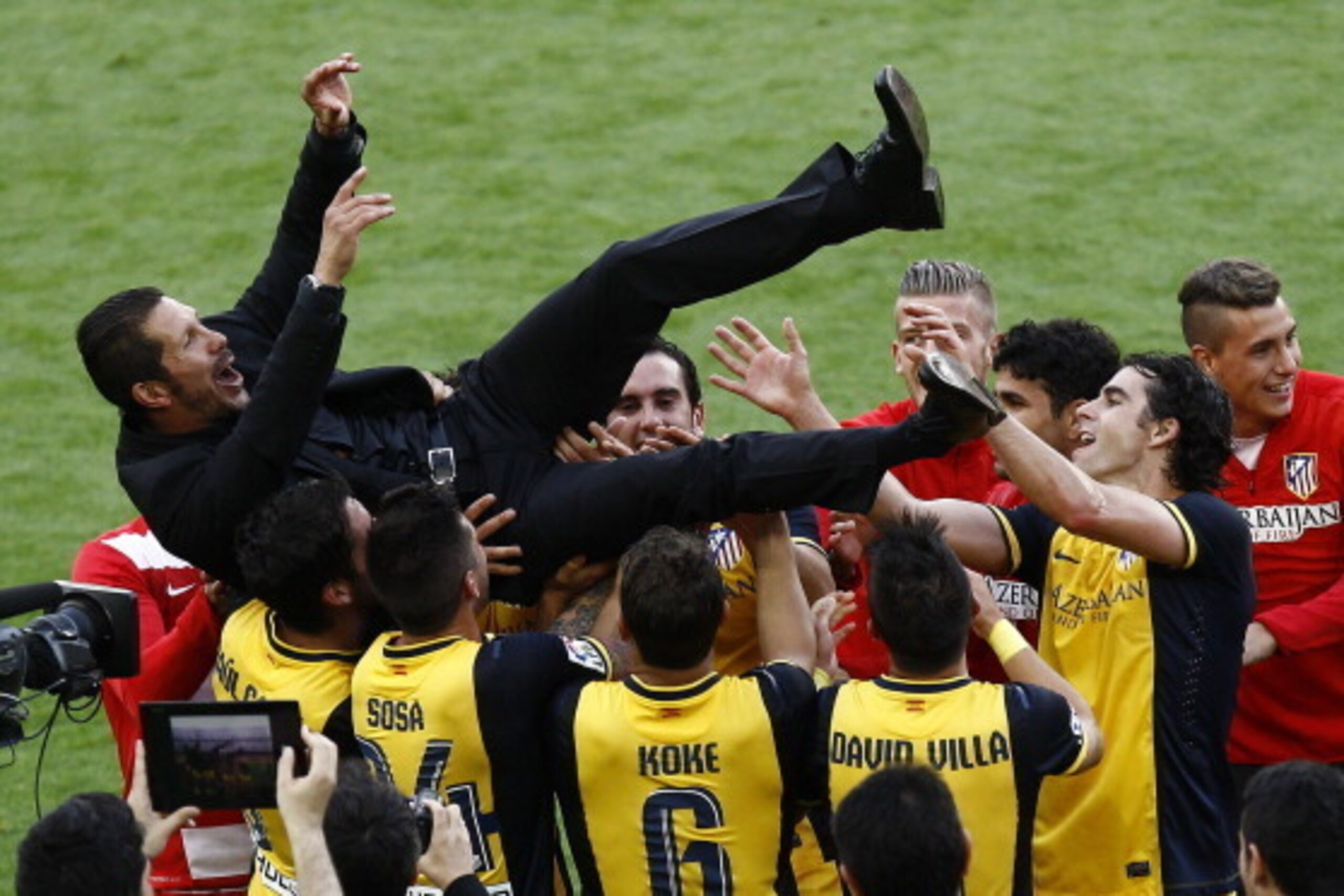 Atletico Madrid's Argentinian coach Diego Simeone is tossed by teammates as they celebrate their Spanish league title at the end of the Spanish league football match FC Barcelona vs Club Atletico de Madrid at the Camp Nou stadium in Barcelona on May 17, 2