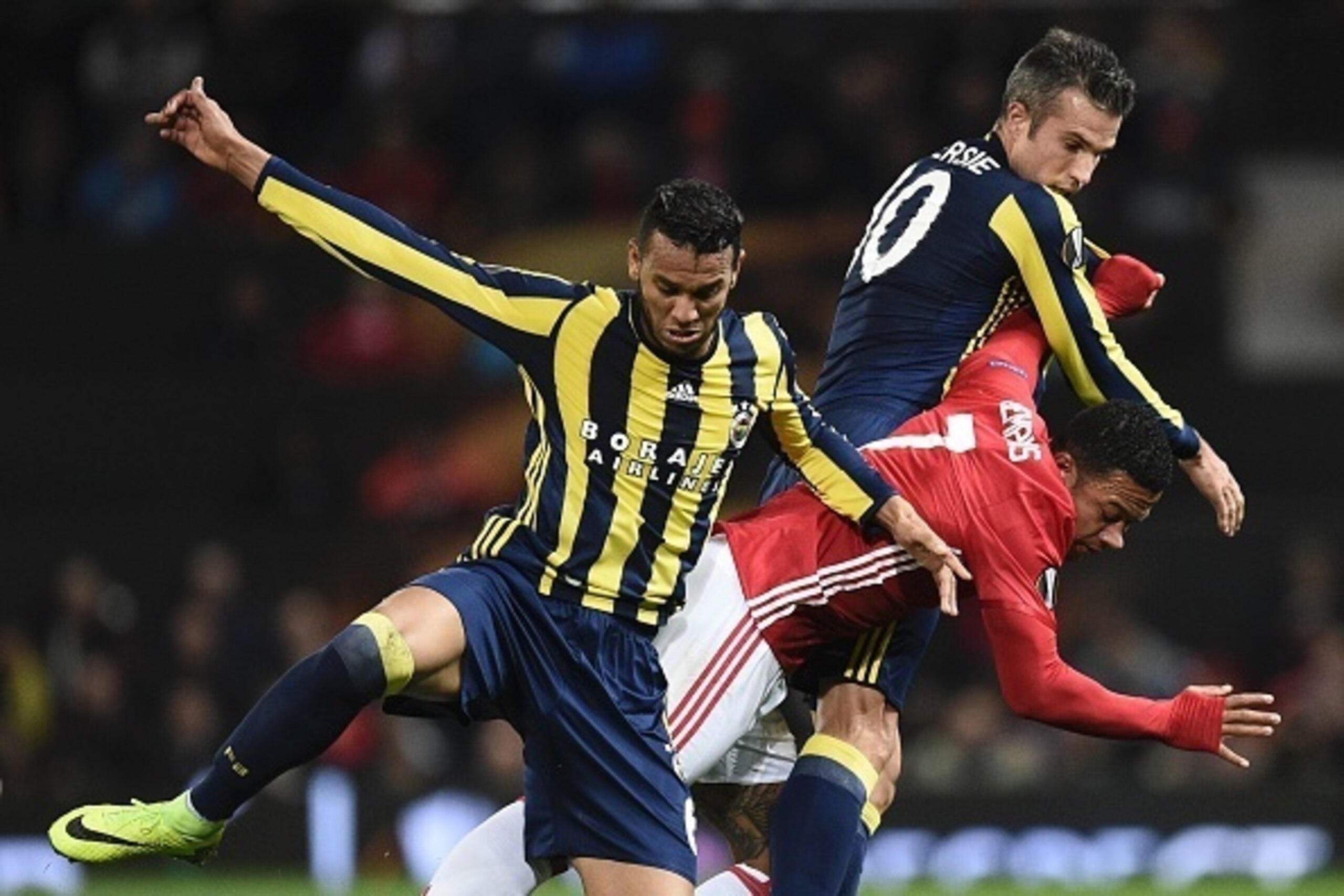 Manchester United's Dutch midfielder Memphis Depay (C) goes down under the challenge of Fenerbahce's Dutch forward Robin van Persie (R) and Fenerbahce's Brazilian midfielder Souza (L) during the UEFA Europa League group A football match between Manchester