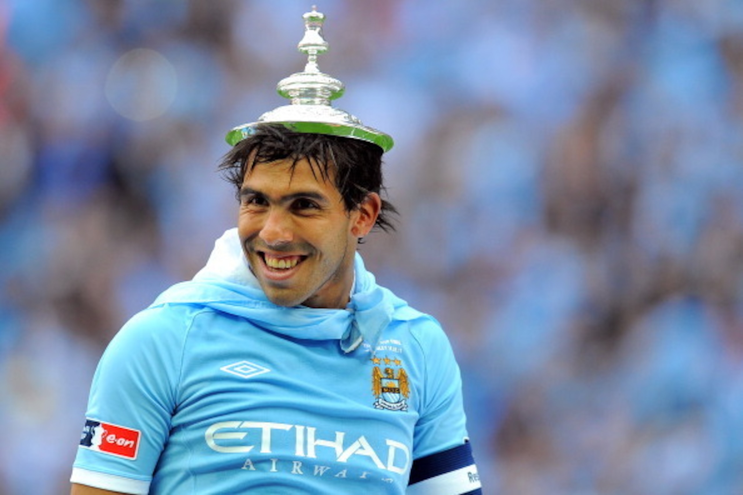 Manchester City's Argentinian footballer Carlos Tevez wears the top of the FA Cup trophy on his head after his team beat Stoke 1-0 during the FA Cup final football match between Manchester City and Stoke City at Wembley Stadium in London, on May 14, 2011.