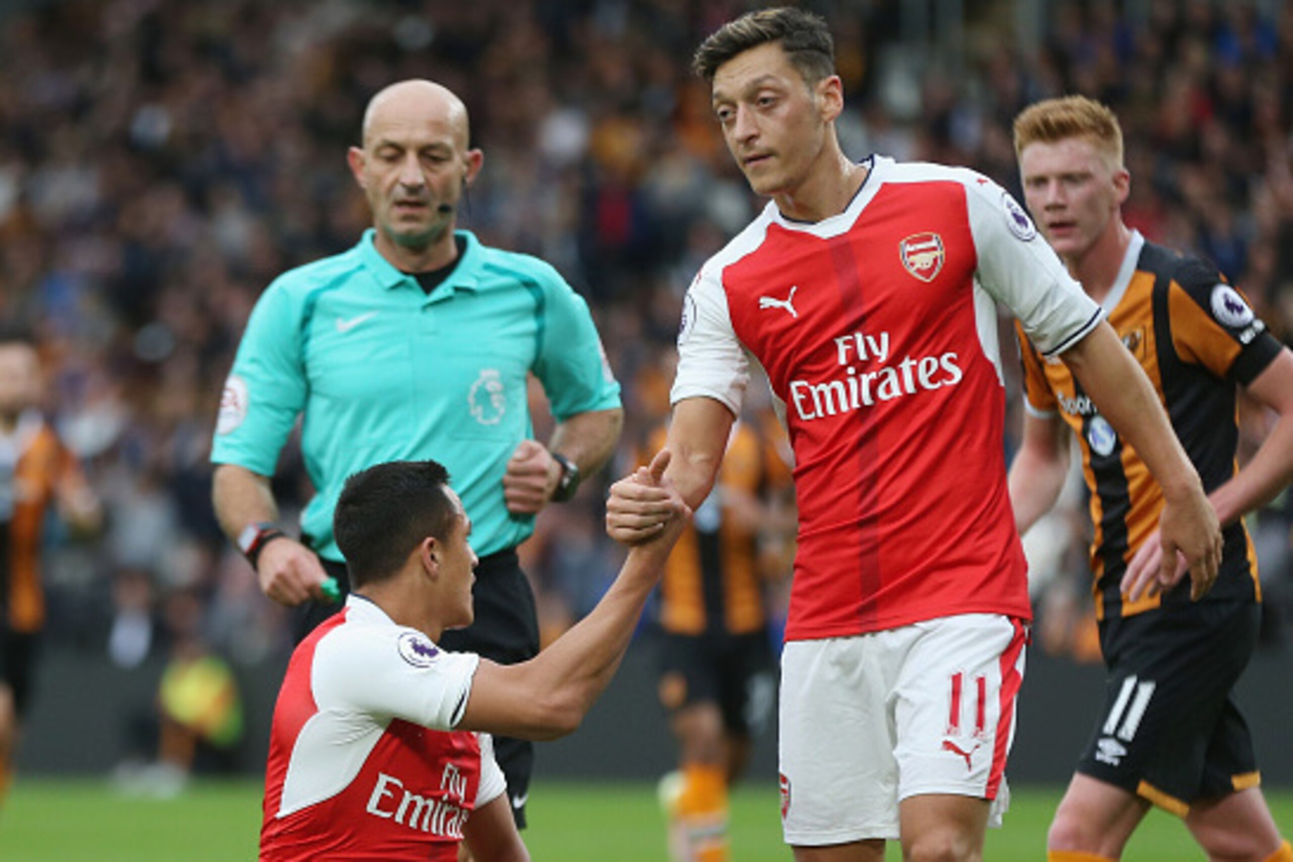 HULL, ENGLAND - SEPTEMBER 17: Mesut Ozil of Arsenal helps up team mae Alexis Sanchez during the Premier League match between Hull City and Arsenal at KCOM Stadium on September 17, 2016 in Hull, England.  (Photo by Alex Morton/Getty Images)