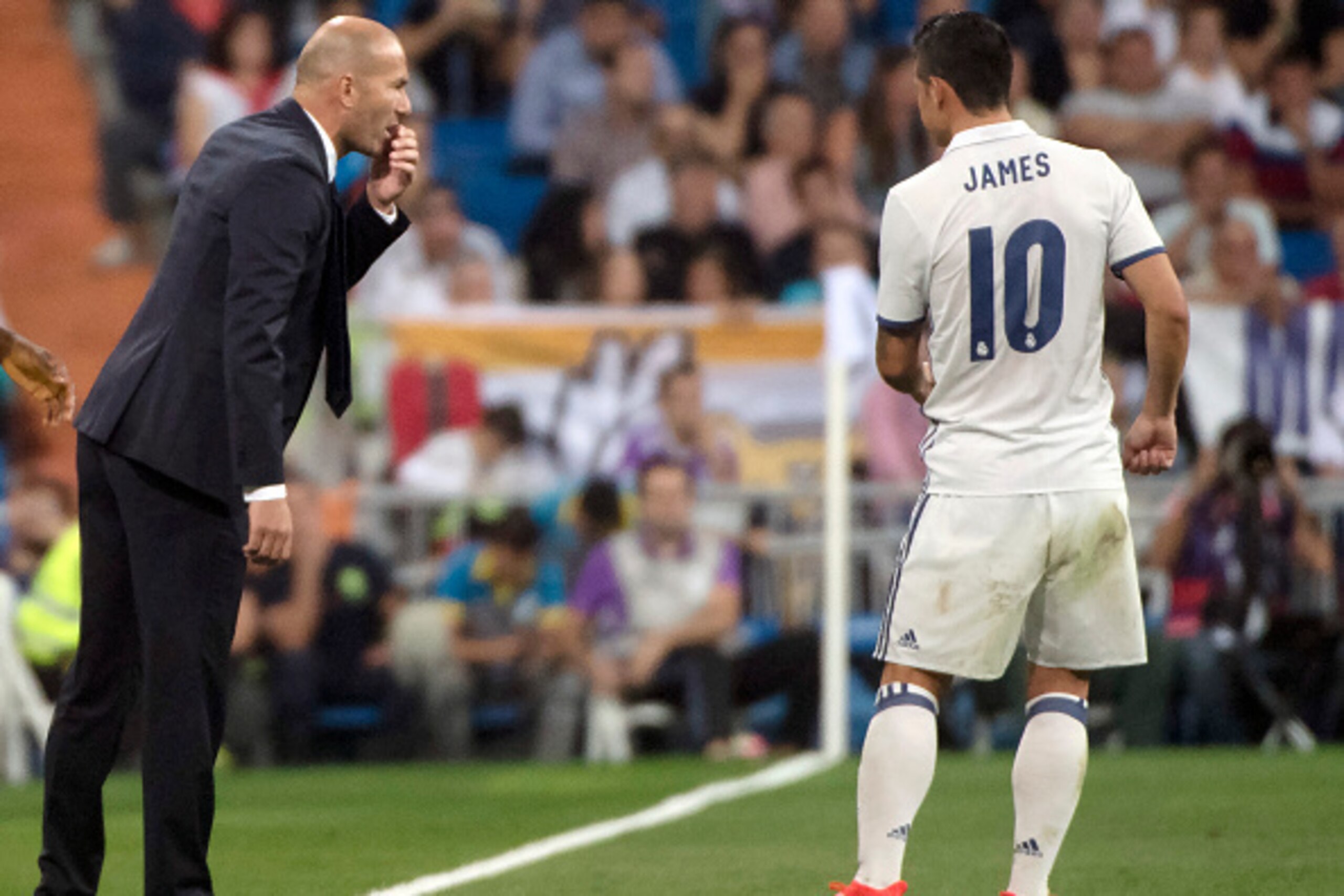 Real Madrid's French coach Zinedine Zidane (L) talks with Real Madrid's Colombian midfielder James Rodriguez during the Spanish league football match Real Madrid CF vs Villarreal CF at the Santiago Bernabeu stadium in Madrid on September 21, 2016. / AFP /