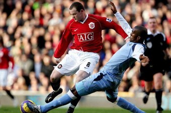Manchester, UNITED KINGDOM:  Manchester United's Wayne Rooney (L) is tackled by Manchester City's Sylvain Distin during their English Premiership football match at Old Trafford, in Manchester, 09 December 2006. AFP PHOTO/PAUL ELLIS Mobile and website use 