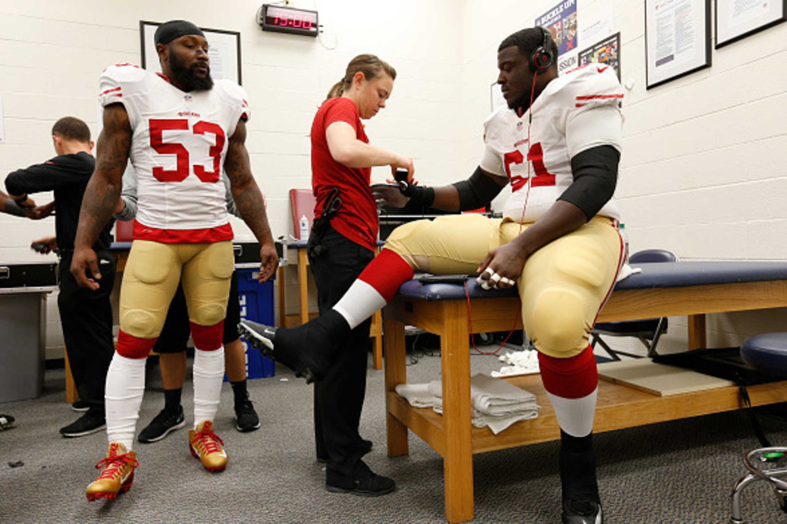SEATTLE, WA - NOVEMBER 22: Assistant Athletics Trainer Laura Schnettgoecke of the San Francisco 49ers taps up Andrew Tiller #61 in the locker room as NaVorro Bowman #53 watches, prior to the game against the Seattle Seahawks at CenturyLink Field on Novemb