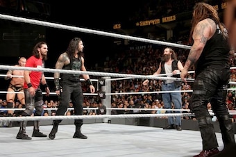 The Wyatt Family surrounds Seth Rollins and Roman Reigns.