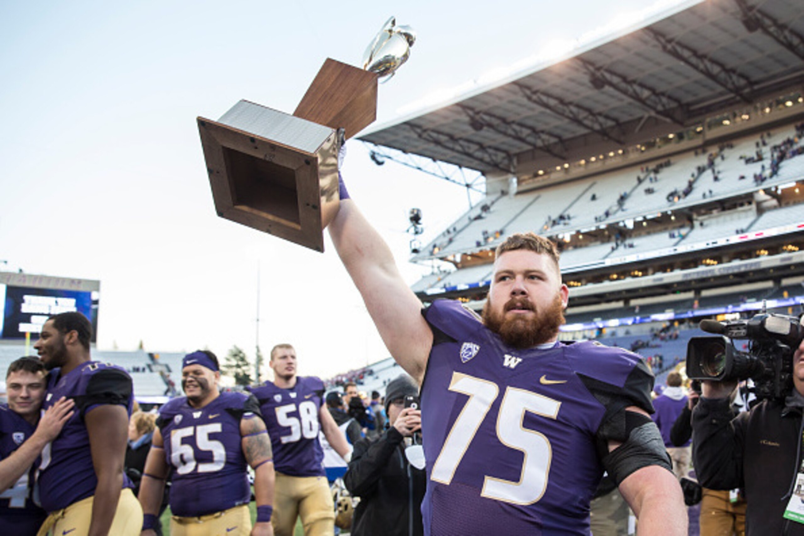 SEATTLE, WA - NOVEMBER 27: Offensive lineman Jesse Sosebee #75 of the Washington Huskies walks off the field with the Apple Cup after the Huskies defeated the Washington State Cougars in a football game at Husky Stadium on November 27, 2015 in Seattle, Wa