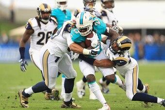 LOS ANGELES, CA - NOVEMBER 20:  T.J. McDonald #25 (R) and Aaron Donald #99 of the Los Angeles Rams takes down Jay Ajayi #23 of the Miami Dolphins during the first quarter of the game at Los Angeles Coliseum on November 20, 2016 in Los Angeles, California.