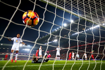 LIVERPOOL, ENGLAND - NOVEMBER 26:  Jordan Pickford of Sunderland dives in vain as Divock Origi of Liverpool scores his team's first goal during the Premier League match between Liverpool and Sunderland at Anfield on November 26, 2016 in Liverpool, England