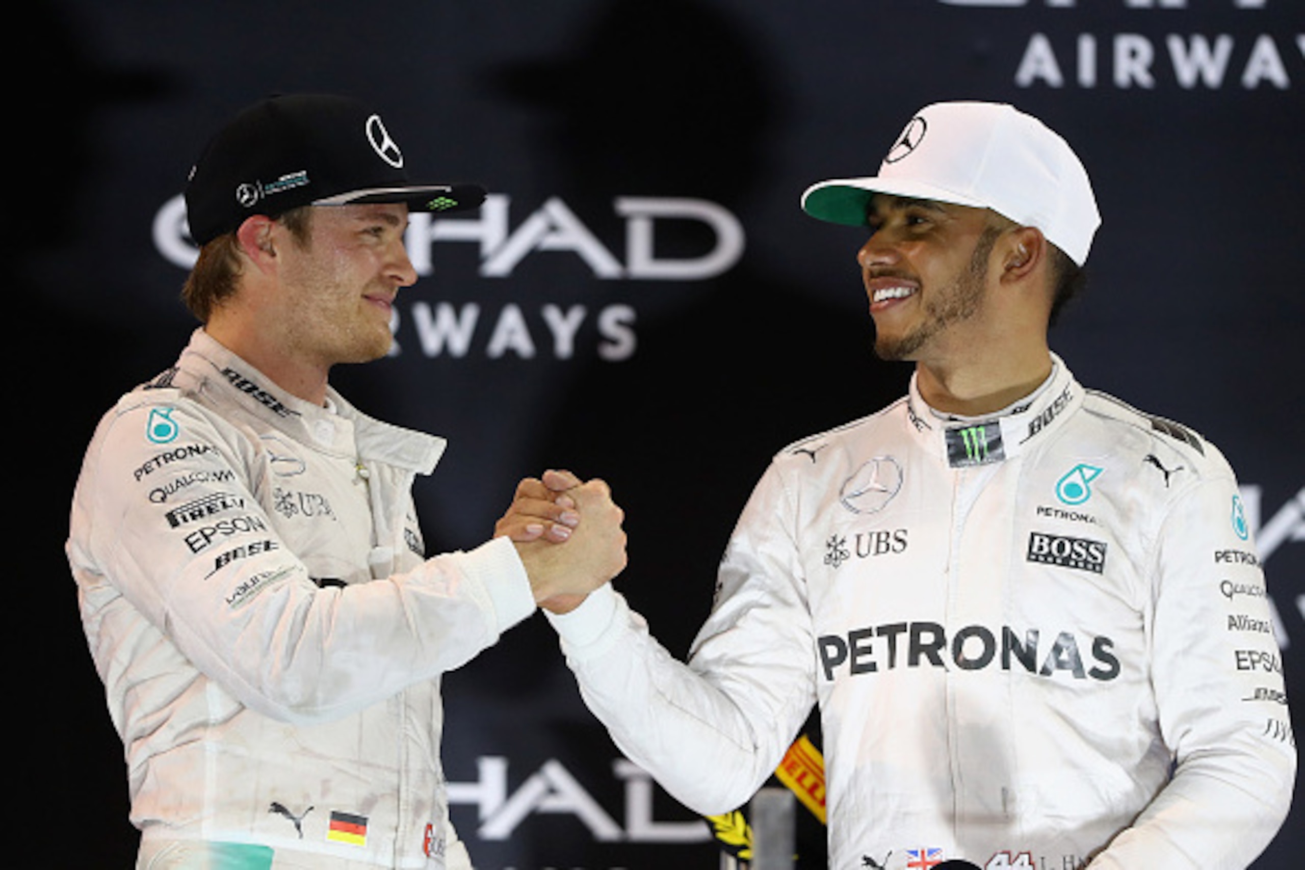 ABU DHABI, UNITED ARAB EMIRATES - NOVEMBER 27:  Race winner Lewis Hamilton of Great Britain and Mercedes GP shakes hands with second place finisher and F1 World Drivers Champion Nico Rosberg of Germany and Mercedes GP on the podium  during the Abu Dhabi F