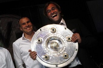 Juergen Klopp (R), coach of German soccer champion Borussia Dortmund, presents the German soccer championship trophy together with his midfielder Kevin Grosskreutz prior to a dinner after the German first division Bundesliga football match Borussia Dortmu