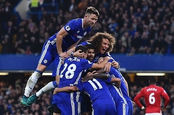 Chelsea's English defender Gary Cahill (top) jumps onto the huddle to join the celebrates after Chelsea's French midfielder N'Golo Kante scored their fourth goal during the English Premier League football match between Chelsea and Manchester United at Sta