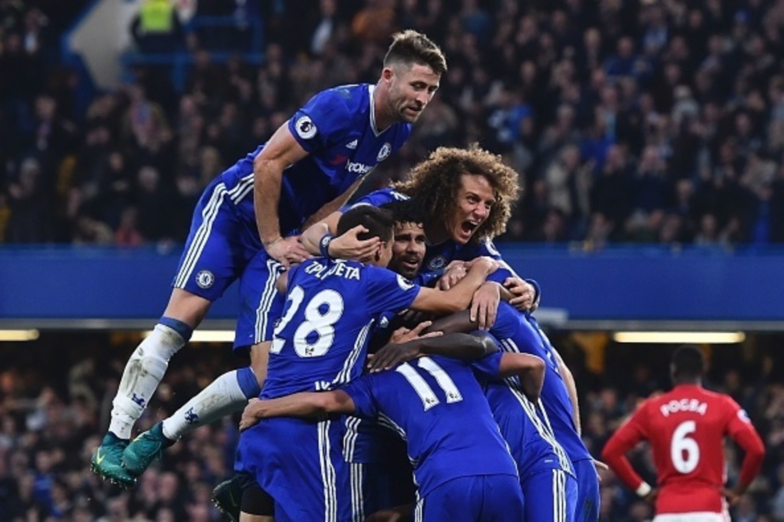 Chelsea's English defender Gary Cahill (top) jumps onto the huddle to join the celebrates after Chelsea's French midfielder N'Golo Kante scored their fourth goal during the English Premier League football match between Chelsea and Manchester United at Sta