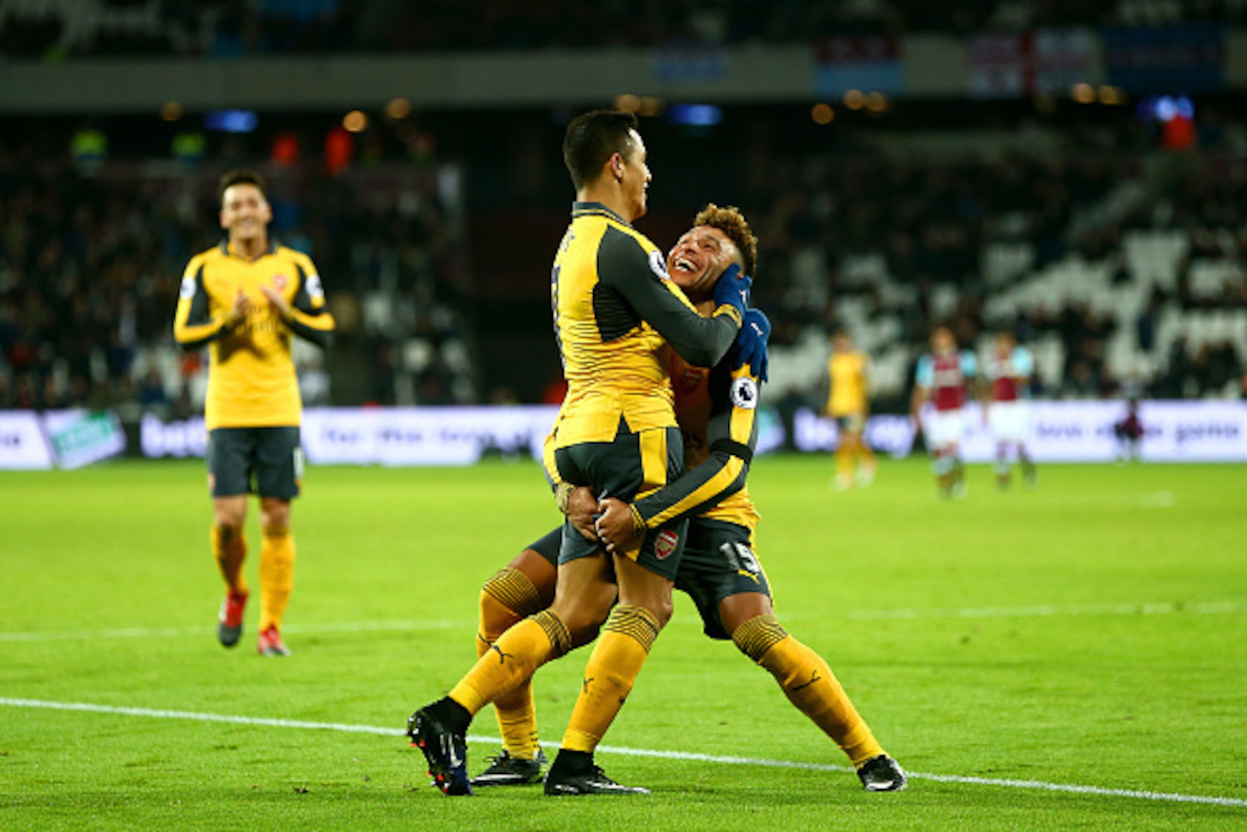 LONDON, ENGLAND - DECEMBER 03:  Alexis Sanchez of Arsenal celebrates with Alex Oxlade-Chamberlain after scoring his team's fifth goal and completes his hat trick during the Premier League match between West Ham United and Arsenal at London Stadium on Dece