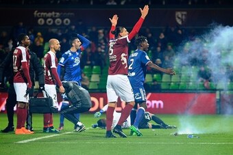 Metz' and Lyon's players reacts after a firecracker has exploded on the pitch during the French L1 football match between Metz (FCM) and Lyon (OL) on December 3, 2016 at Saint Symphorien stadium in Longeville-Les-Metz, eastern France.  / AFP / JEAN-CHRIST