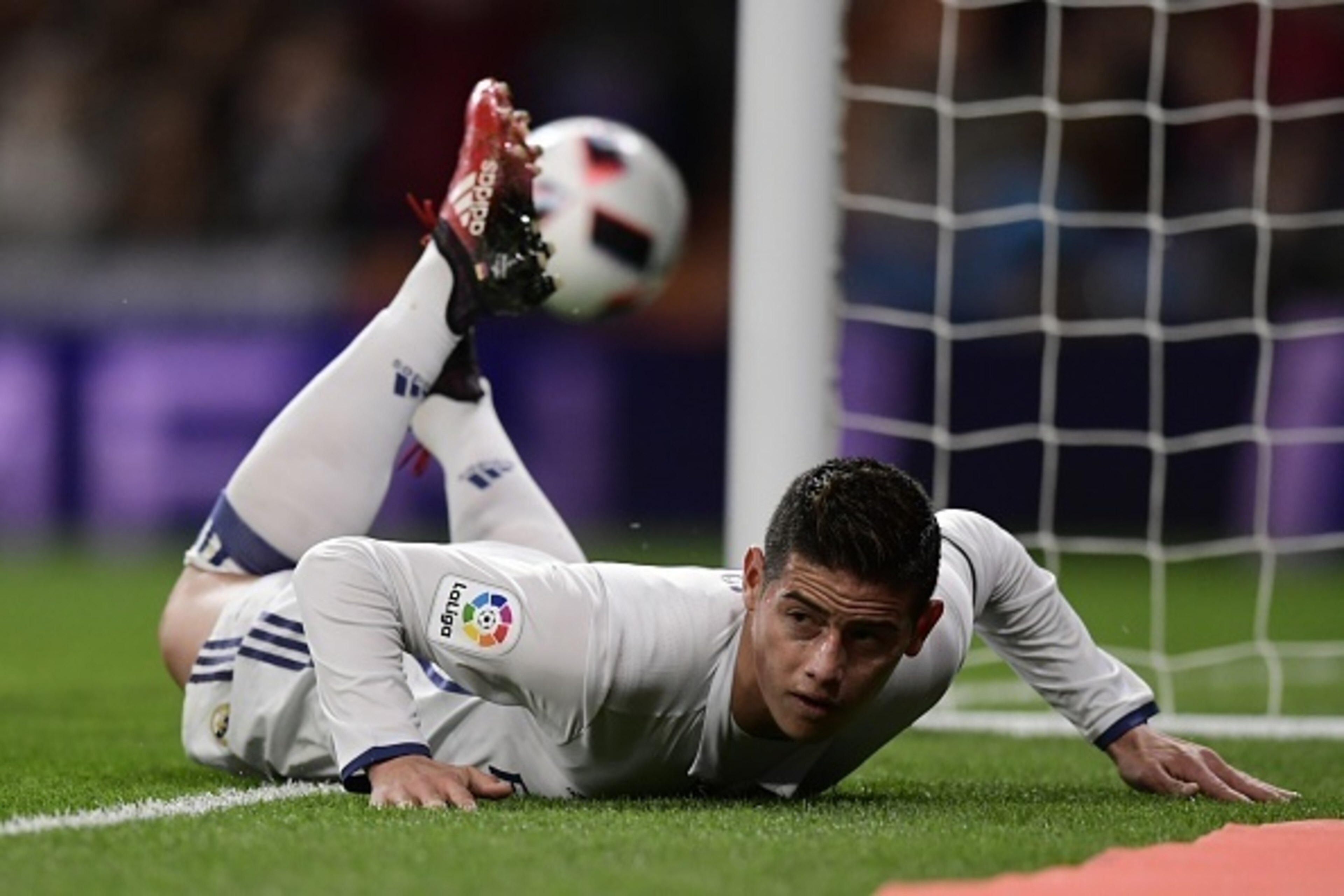 Real Madrid's Colombian midfielder James Rodriguez lies on the ground as he celebrates after scoring during the Spanish Copa del Rey (King's Cup) Round of 32 second leg football match Real Madrid CF vs Cultural y Deportiva Leonesa at the Santiago Bernabeu